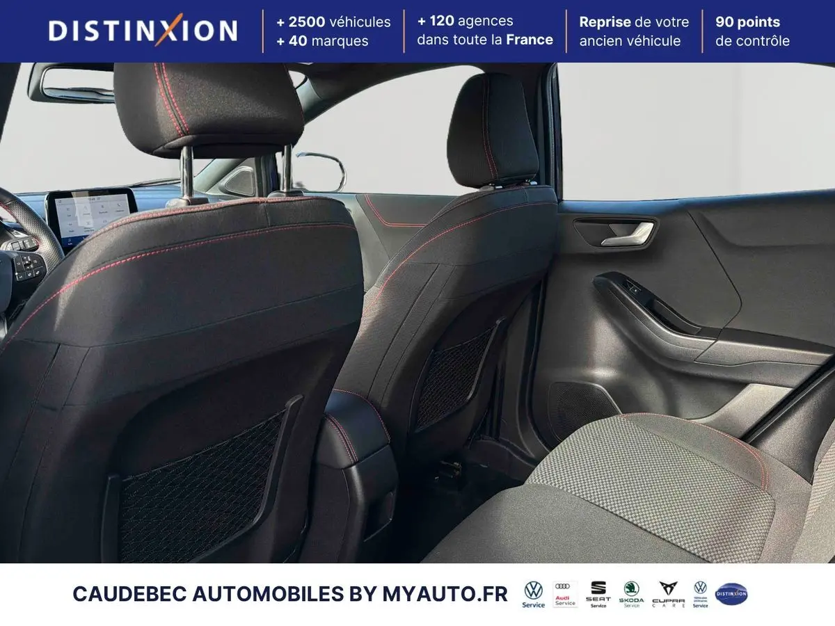 Vue intérieure arrière droite du Ford Puma 2024, sièges sport noirs avec surpiqûres rouges et tableau de bord visible.