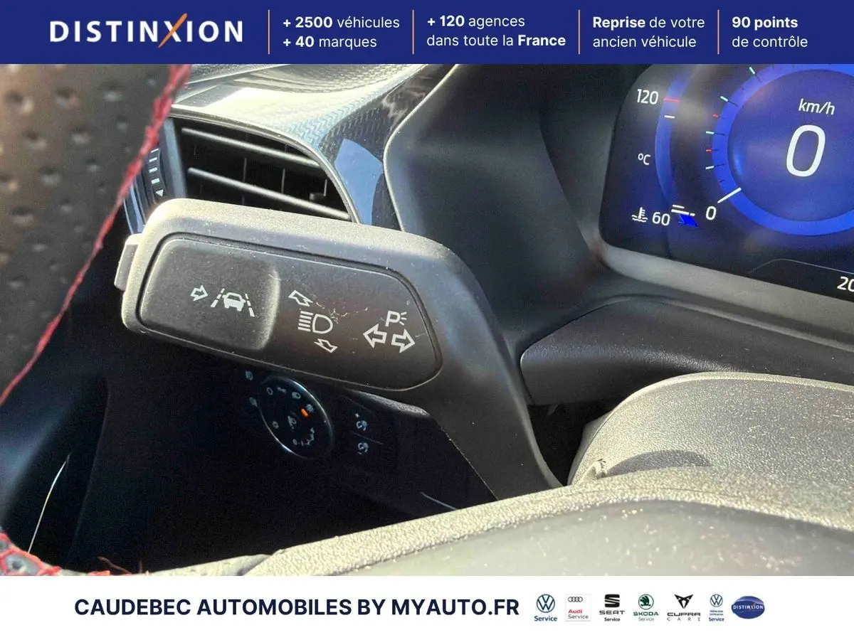 Gros plan sur la manette de clignotants et tableau de bord numérique bleu du Ford Puma 2024, intérieur noir.