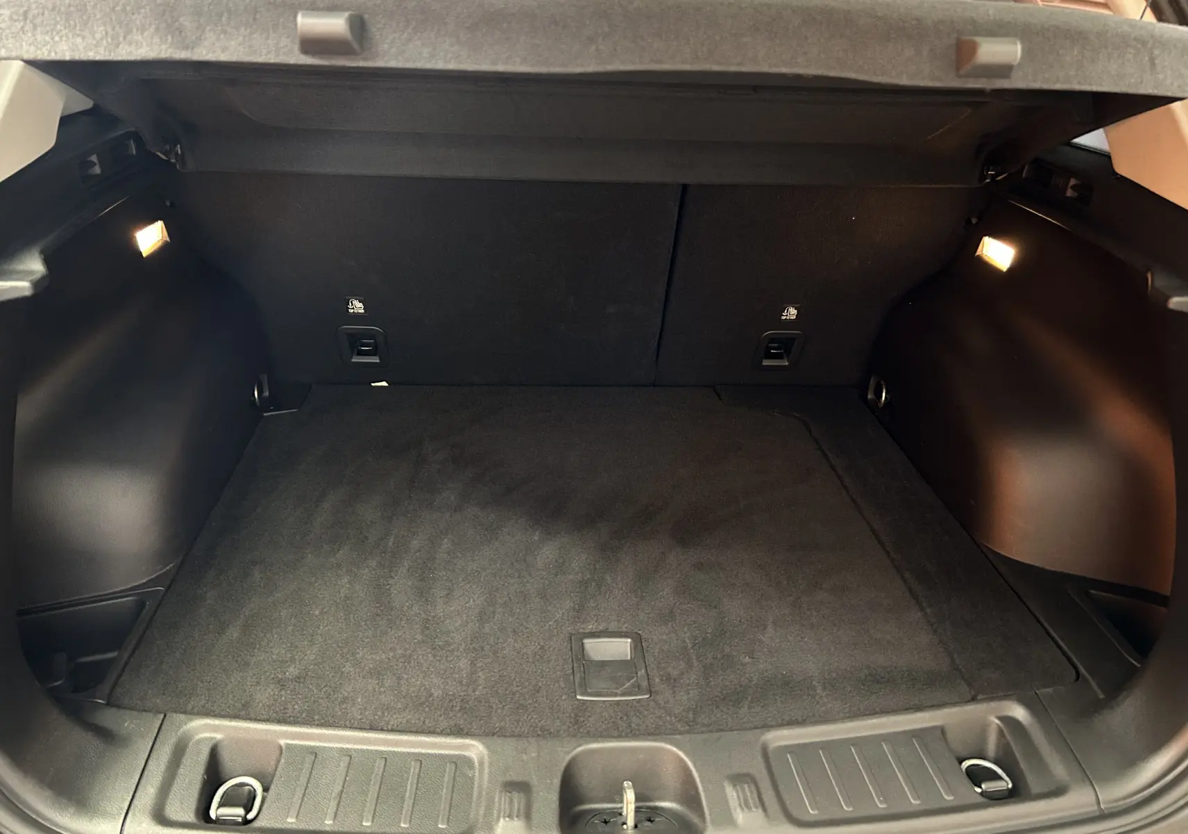 Coffre spacieux noir du Jeep Compass Limited 2021, vu de l'arrière avec éclairage intérieur allumé.