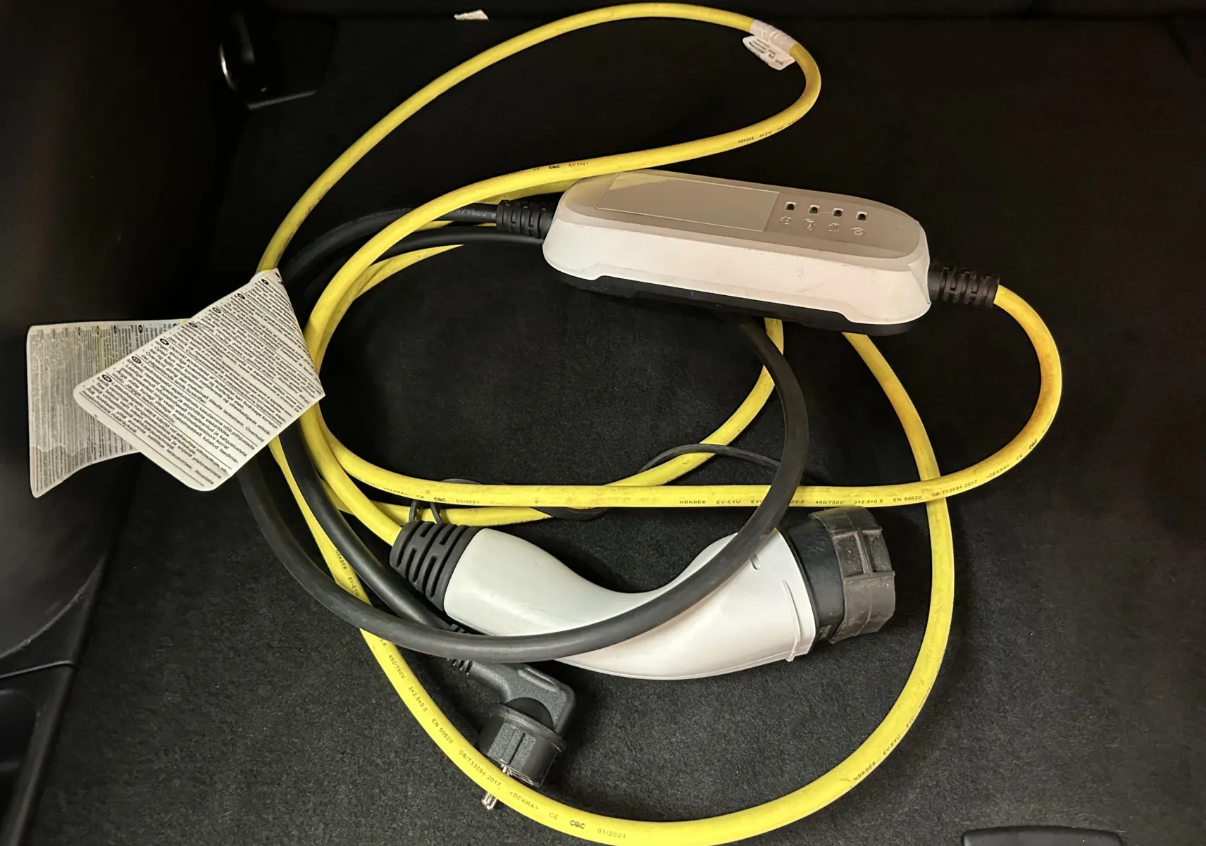Câble de recharge jaune et noir pour Jeep Compass Limited PHEV 2021, posé sur le tapis noir du coffre.