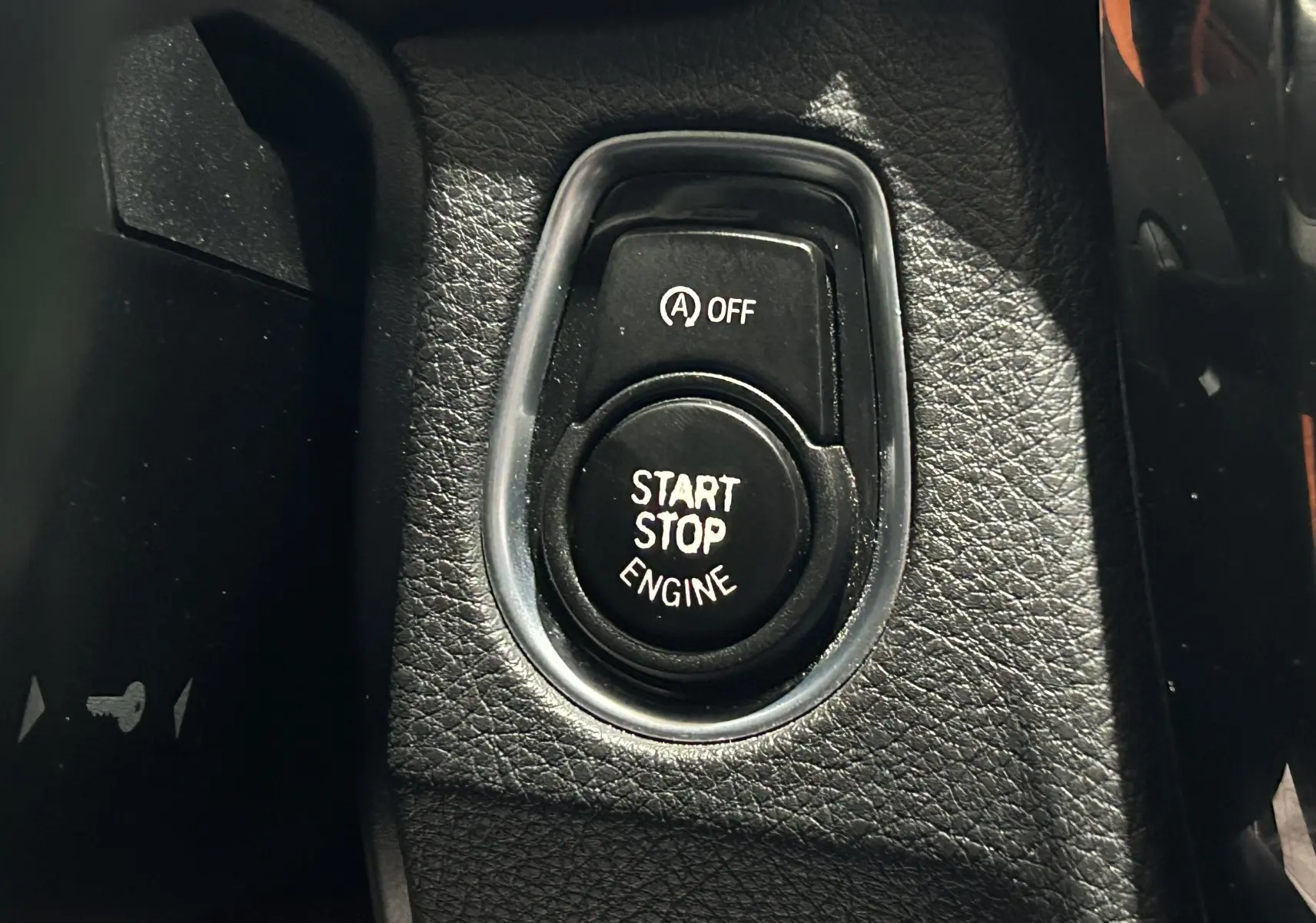 Gros plan sur le bouton Start Stop Engine noir entouré de cuir noir dans une BMW Série 3 blanche de 2018.