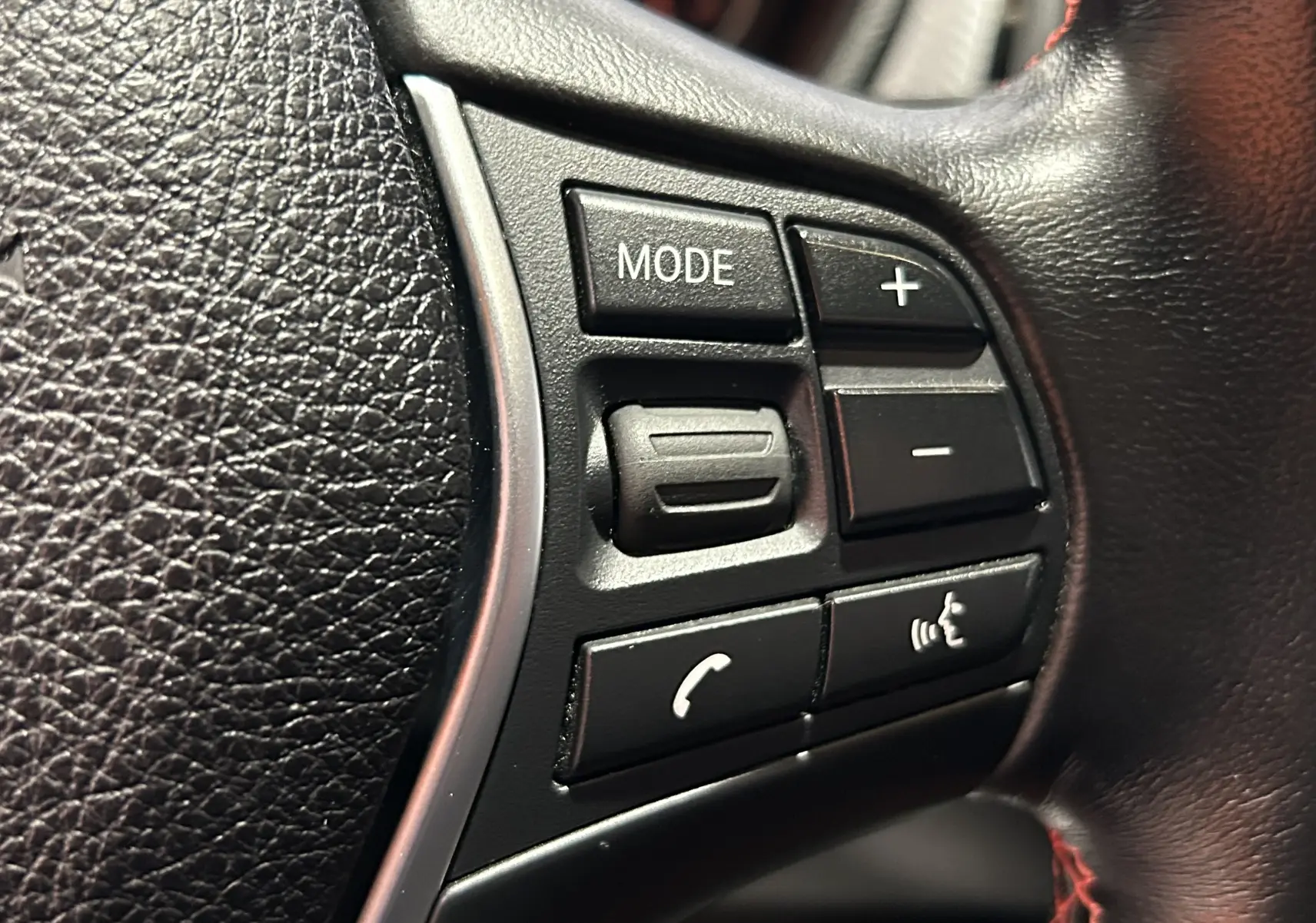 Gros plan sur les commandes du volant en cuir noir de la BMW Série 3 320i blanche, version 2018.