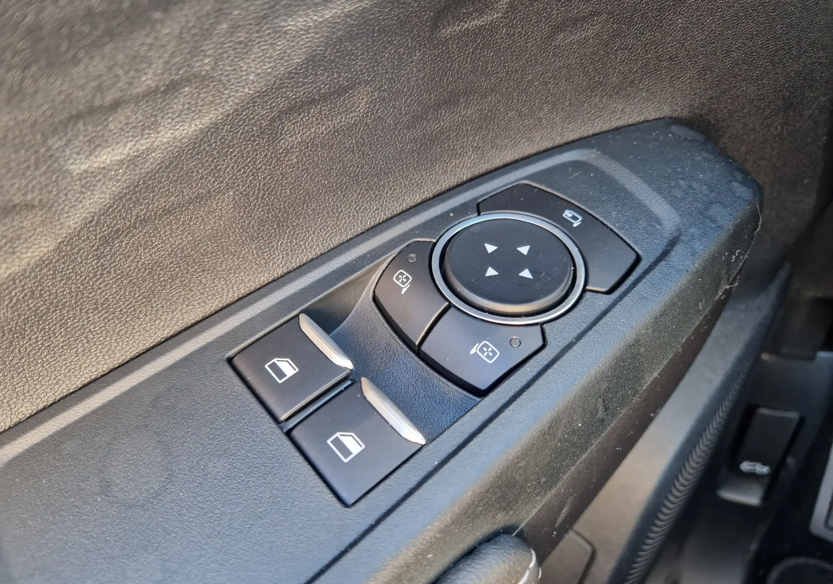 Gros plan sur les commandes de réglage des rétroviseurs et des vitres côté conducteur du Ford Ranger Super Cabine gris carbone.