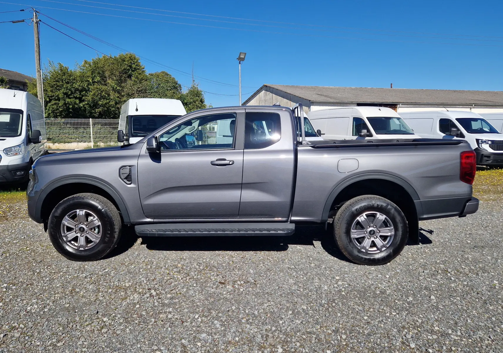 Vue de profil côté gauche d'un Ford Ranger Super Cabine gris carbone 2026 avec benne et jantes alliage.