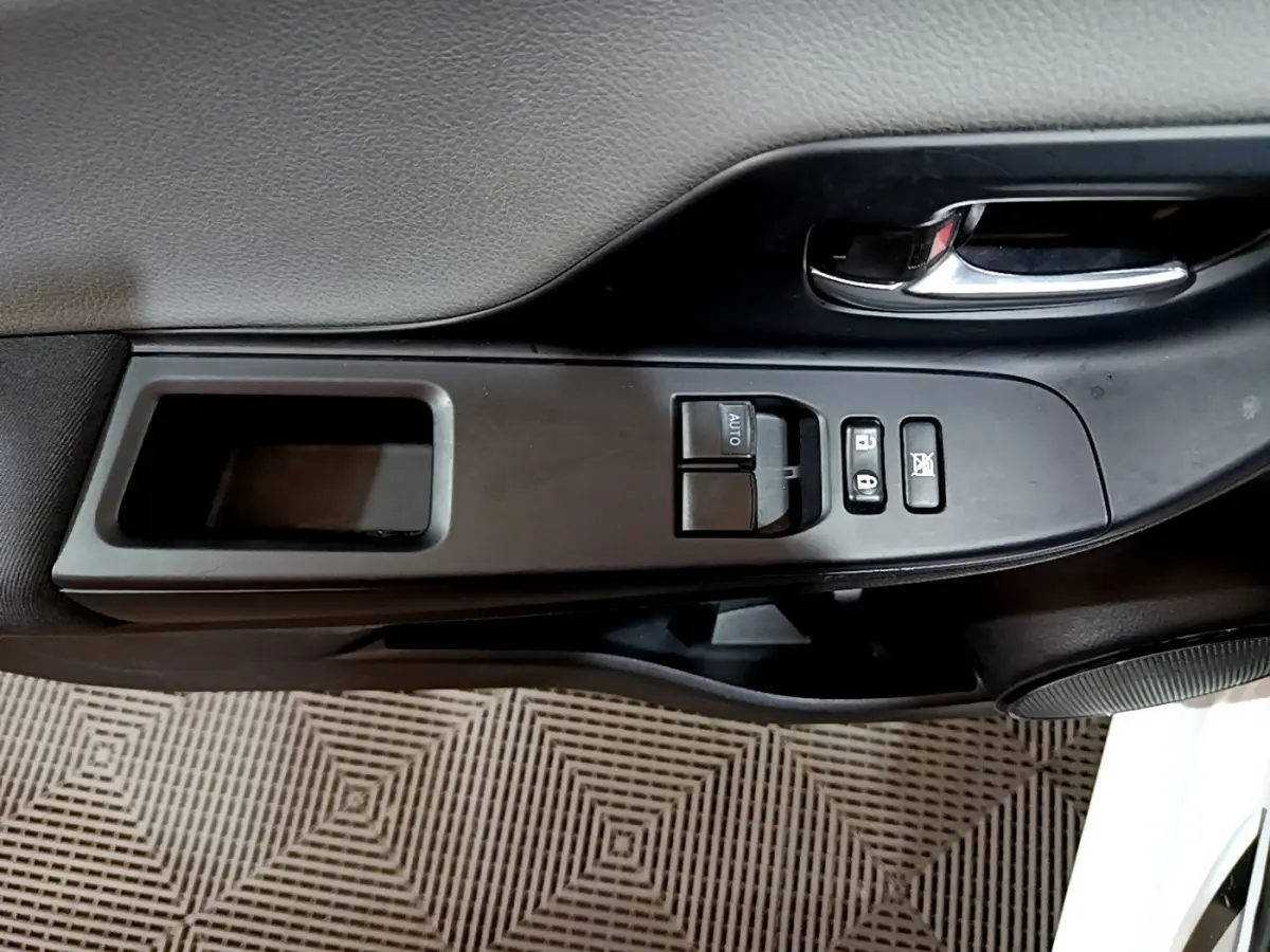 Gros plan sur la commande de lève-vitre côté conducteur de la Toyota Yaris blanche 2020, avec poignée intérieure chromée.