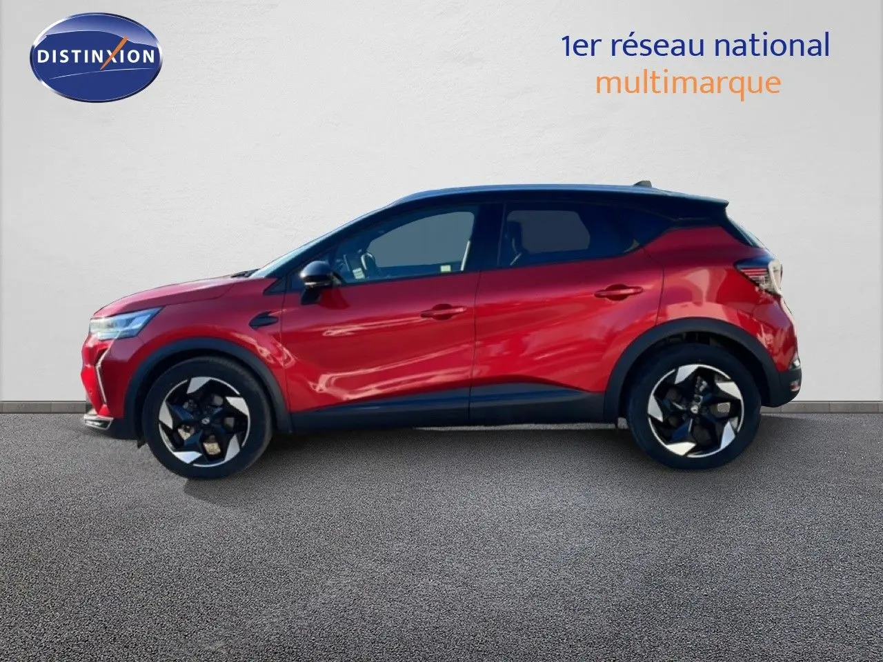 Profil droit du Renault Captur 2025 rouge désir métallisé avec toit noir, roues alliage bicolores et lignes dynamiques.