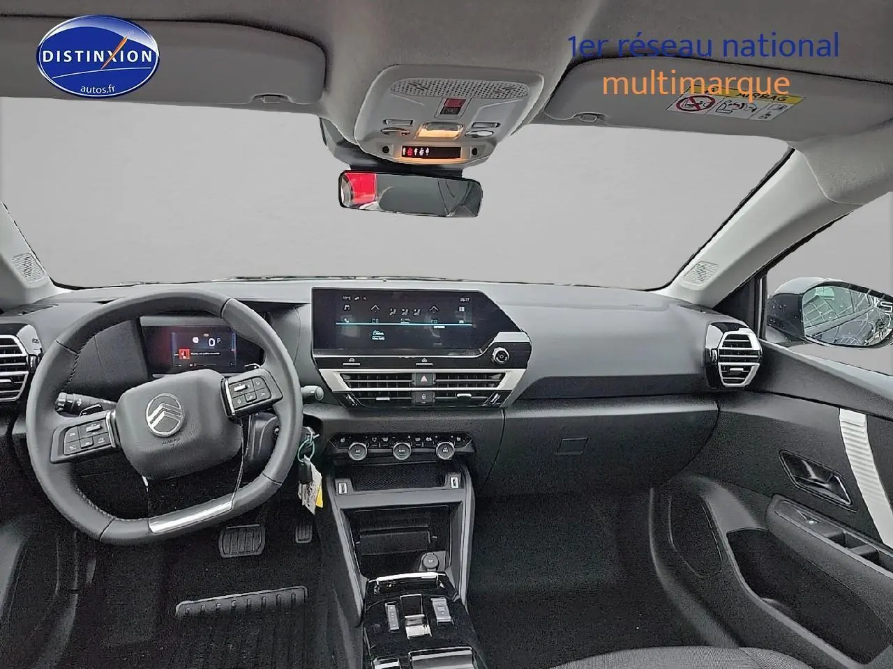 Vue intérieure avant du tableau de bord et volant cuir noir d'une Citroën C4 hybride 2025 avec écran tactile et commandes au volant.