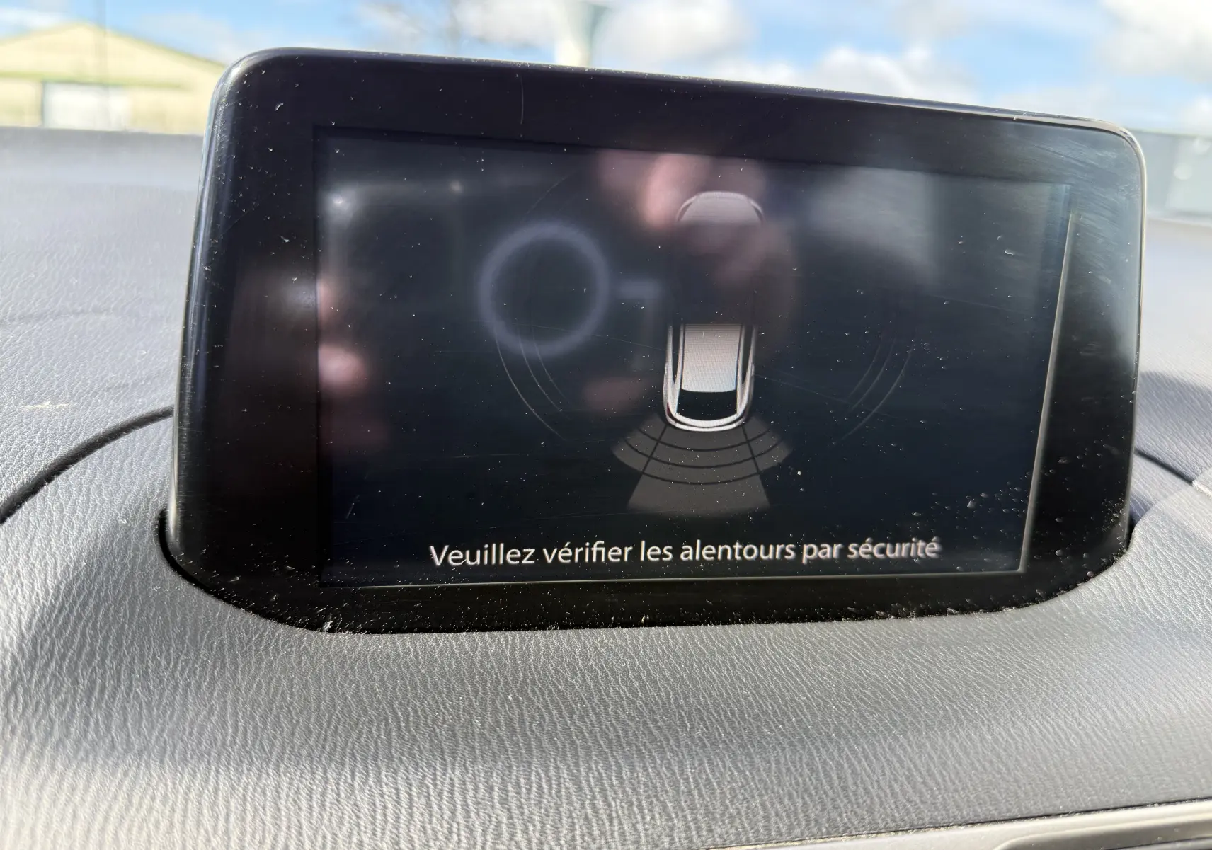 Écran central de la Mazda3 2017 affichant l'alerte de sécurité pour vérifier les alentours du véhicule.