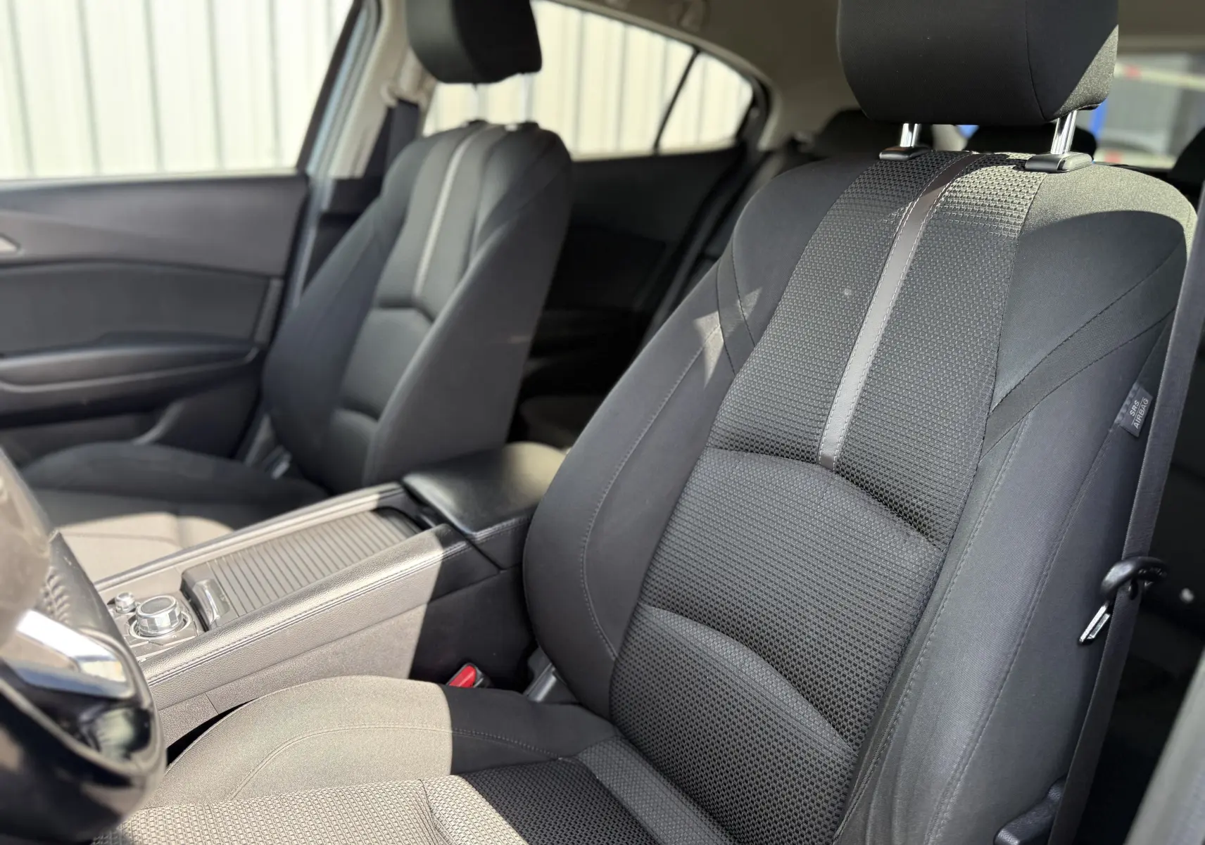 Vue intérieure rapprochée des sièges avant en tissu noir de la Mazda3 2017, côté conducteur et passager.