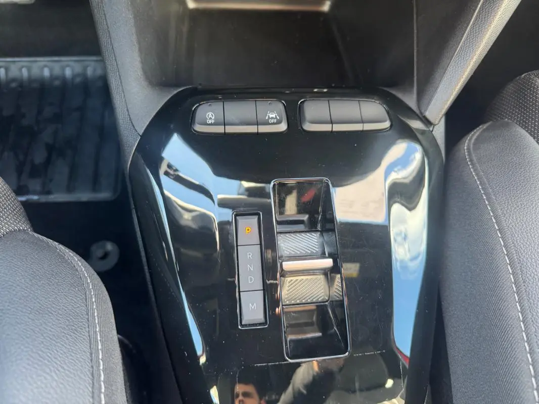 Gros plan sur la console centrale noire de l’Opel Corsa 2025 avec levier de boîte auto et boutons de contrôle.