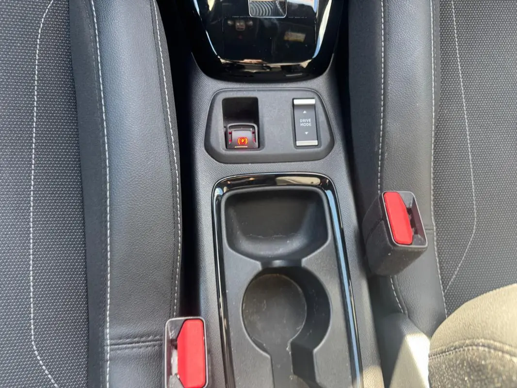 Vue rapprochée du console central noir entre les sièges avant gris d’une Opel Corsa rouge 2025.