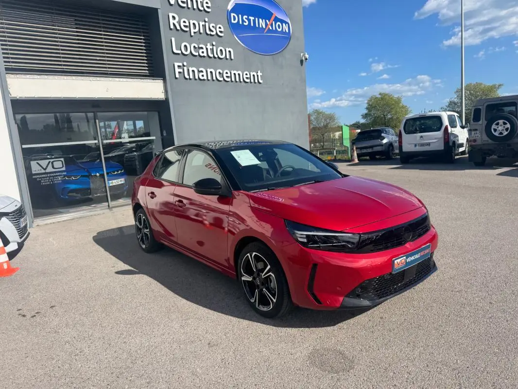 Vue 3/4 avant droite d'une Opel Corsa rouge 2025 avec jantes alliage 17 pouces, calandre noire et toit noir.