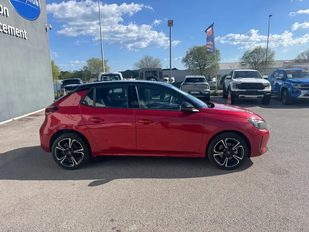 Vue de profil côté gauche d'une Opel Corsa rouge 2025 avec jantes alliage noires et toit noir.
