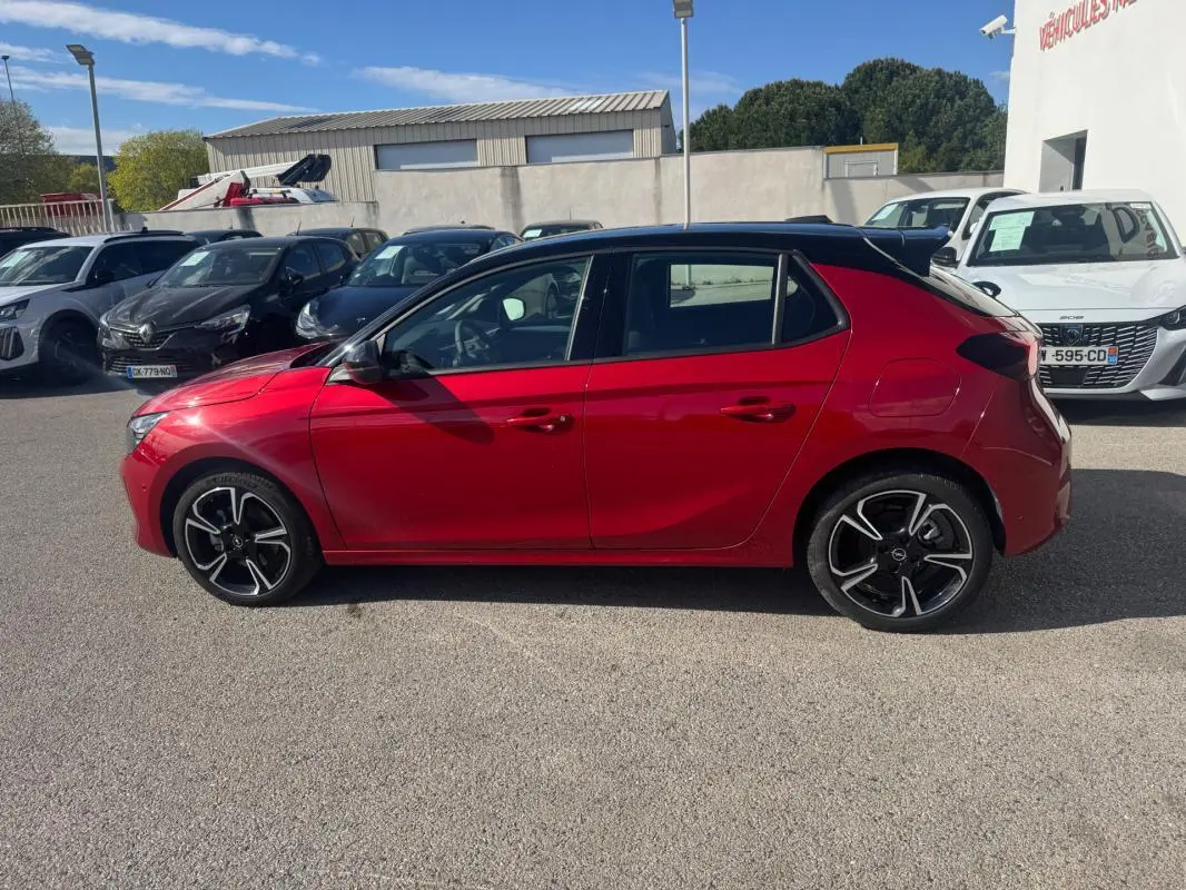 Opel Corsa rouge vue de profil côté gauche, avec jantes alliage noires et toit noir contrasté.