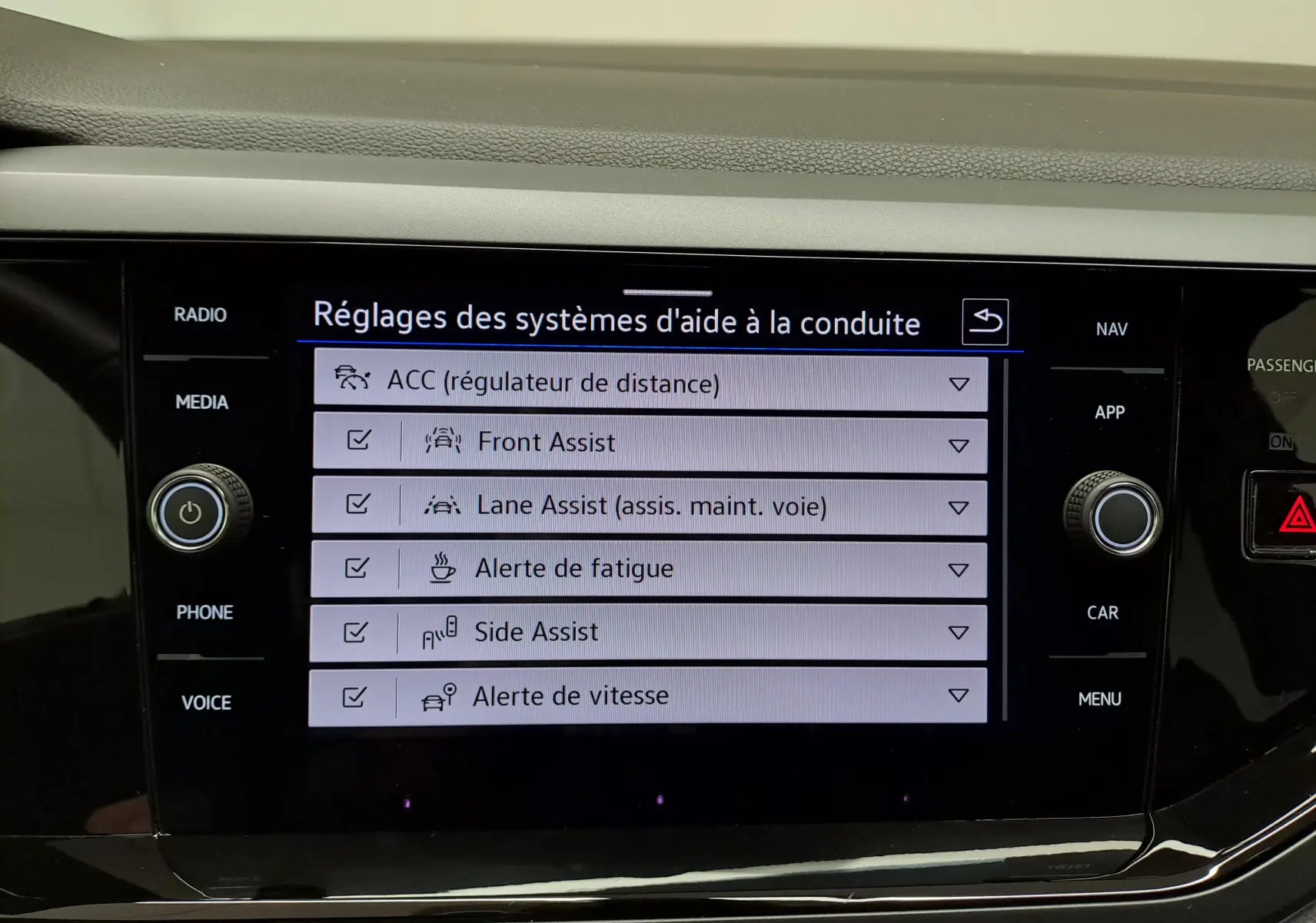 Écran tactile central affichant les réglages des aides à la conduite dans une Volkswagen Polo Bleu Récif.