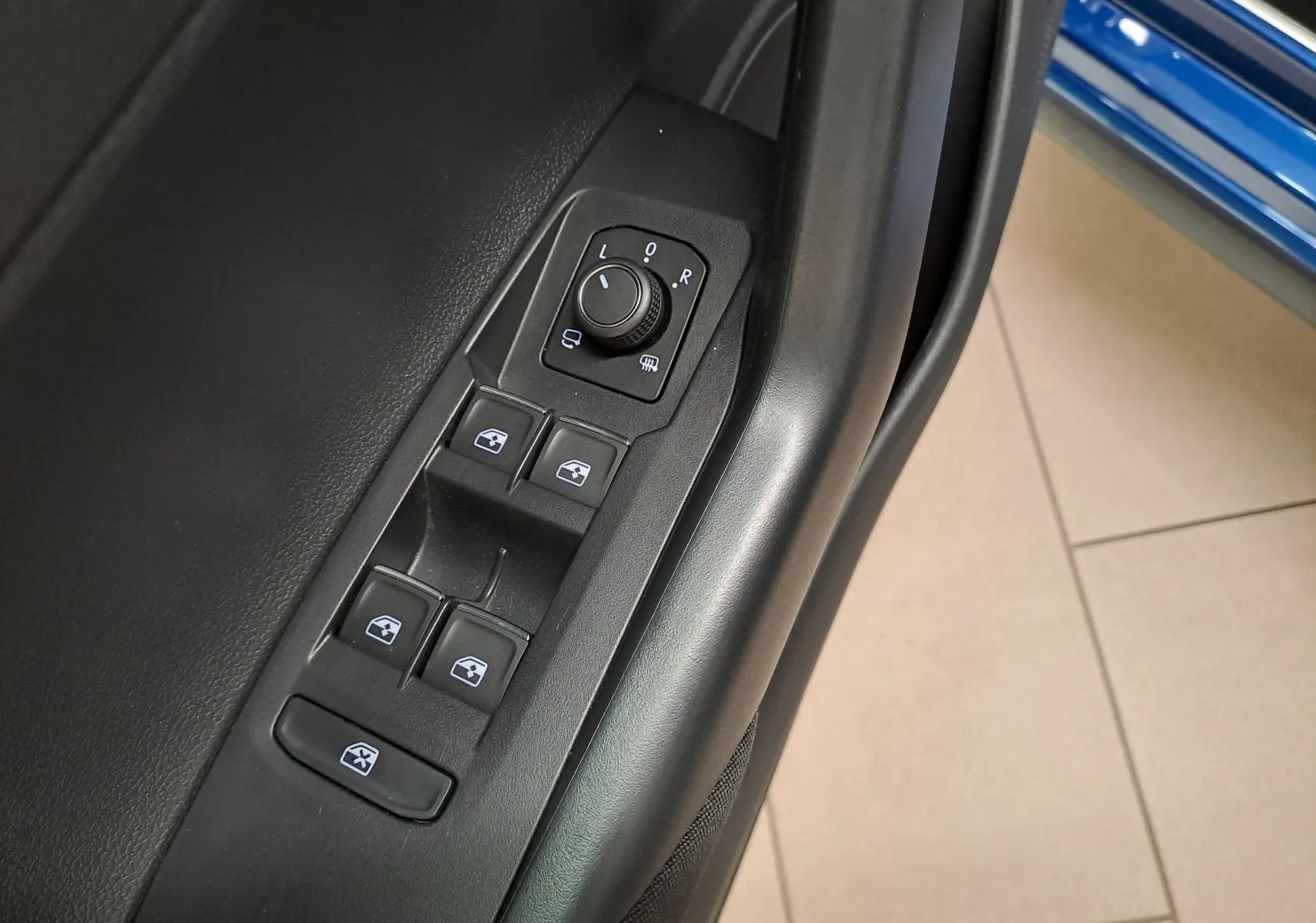 Gros plan sur les commandes de lève-vitres et rétroviseurs côté gauche d'une Volkswagen Polo Bleu Récif 2025.