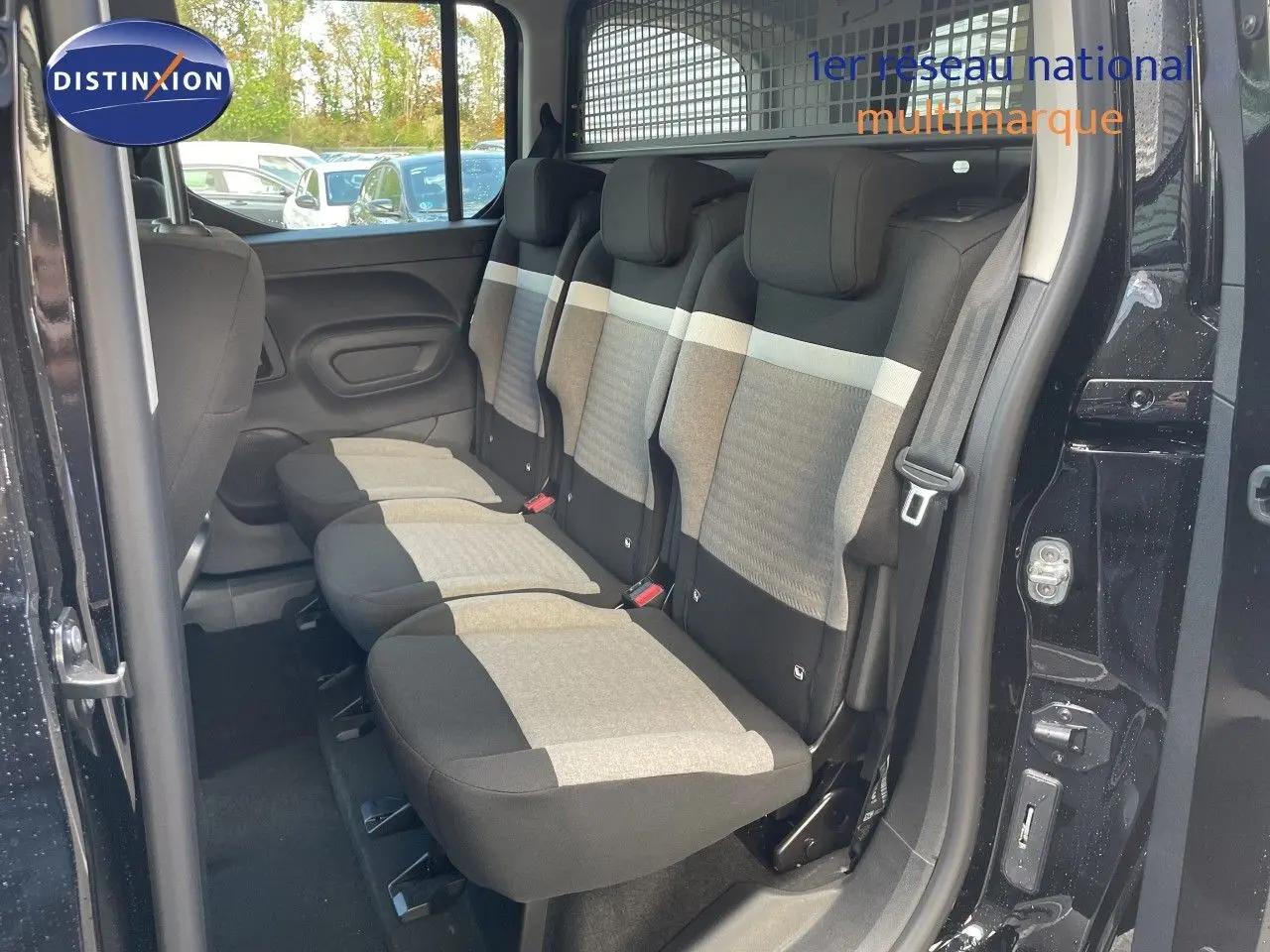 Vue intérieure côté droit montrant la banquette arrière trois places en tissu gris et noir du Citroën Berlingo noir Perla Nera.