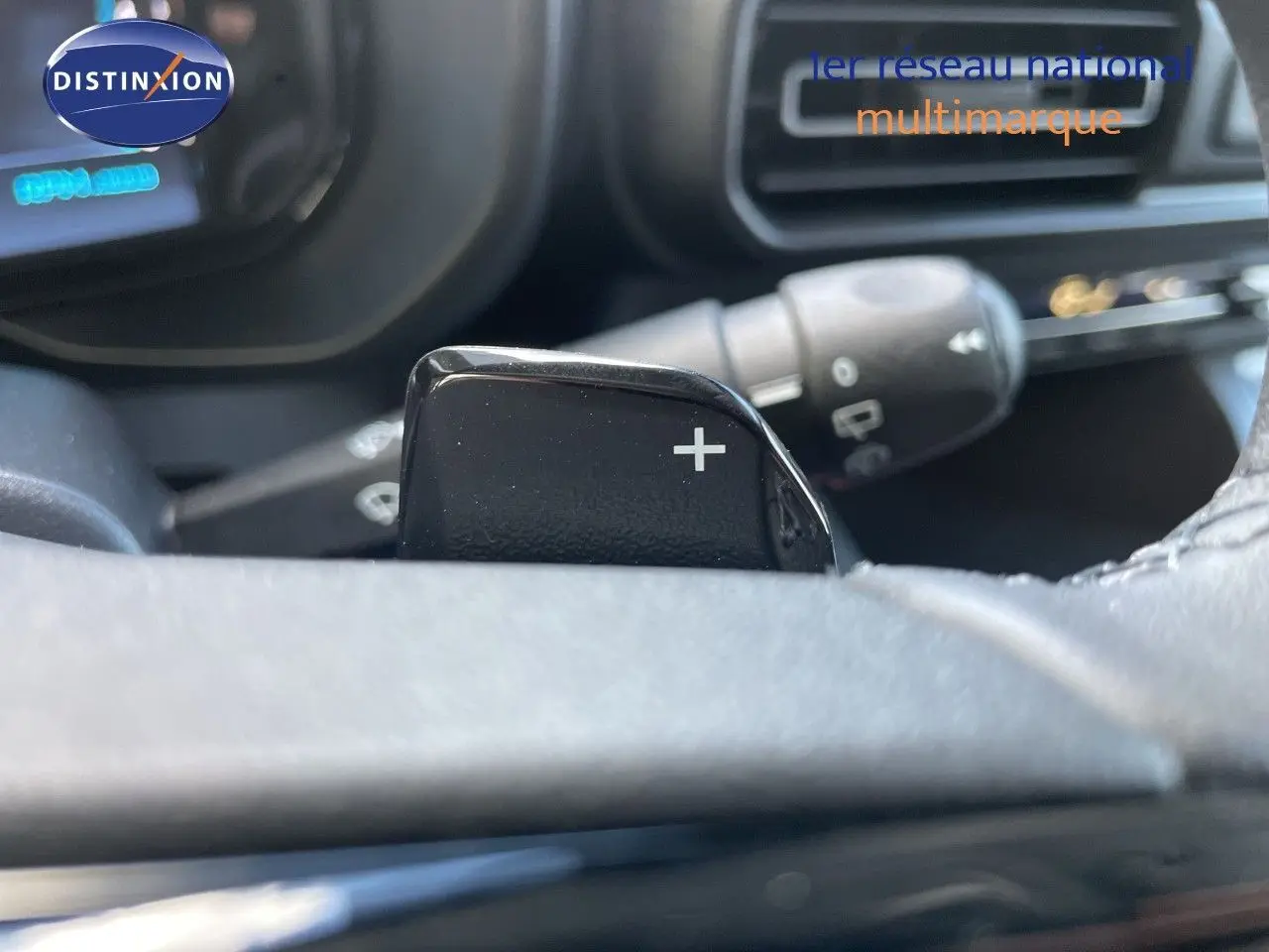Gros plan sur la palette de changement de vitesse "+" du volant d'un Citroën Berlingo noir Perla Nera, intérieur moderne.