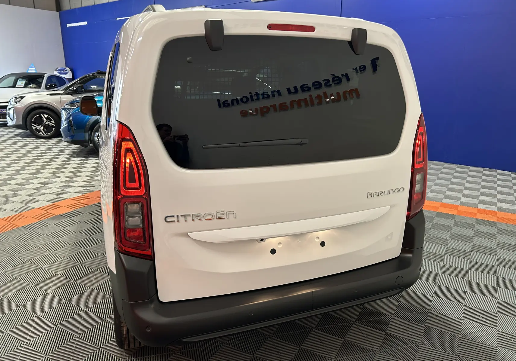 Vue arrière du Citroën Berlingo Multispace blanc Kaolin avec feux LED et lunette arrière surteintée en showroom.