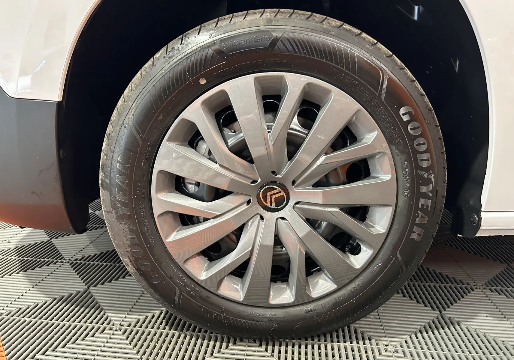 Gros plan sur la roue avant gauche du Citroën Berlingo Multispace blanc Kaolin avec jante argentée et pneu Goodyear.