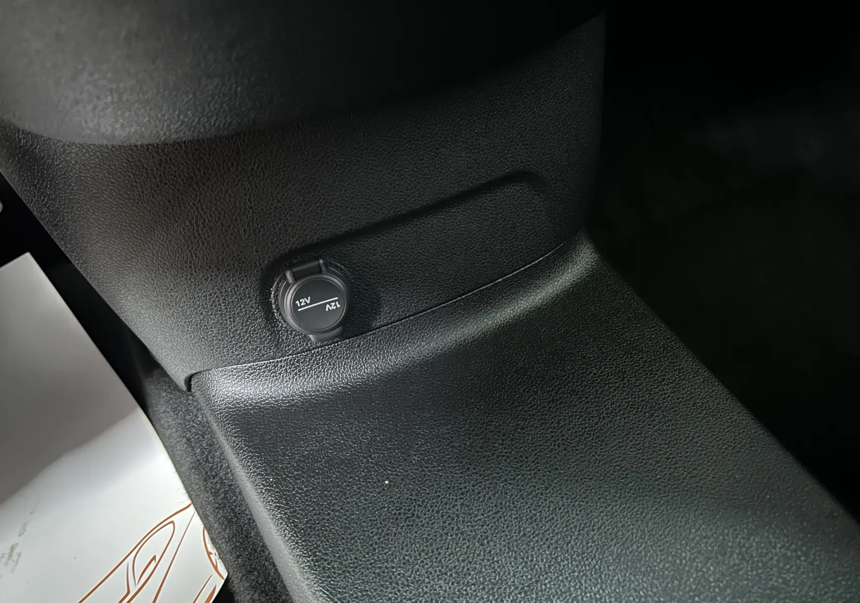 Détail intérieur montrant une prise 12V sur la console centrale noire du Citroën Berlingo Multispace blanc.