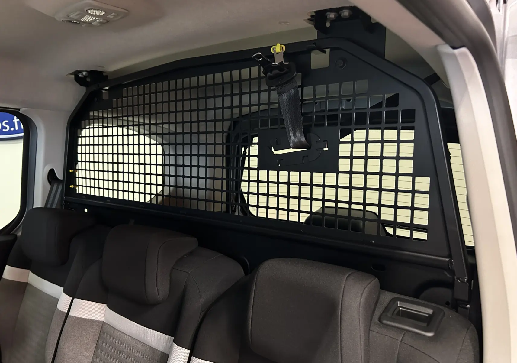 Vue intérieure arrière du Citroën Berlingo Multispace blanc Kaolin, montrant la grille de séparation et les sièges tissu noirs et gris.