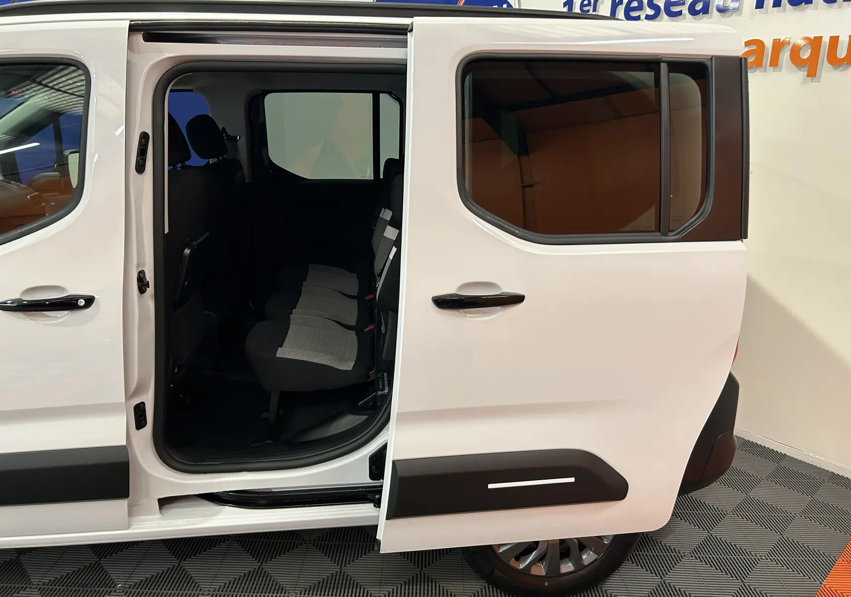 Vue latérale droite du Citroën Berlingo blanc Kaolin avec porte coulissante ouverte dévoilant les sièges arrière en tissu.