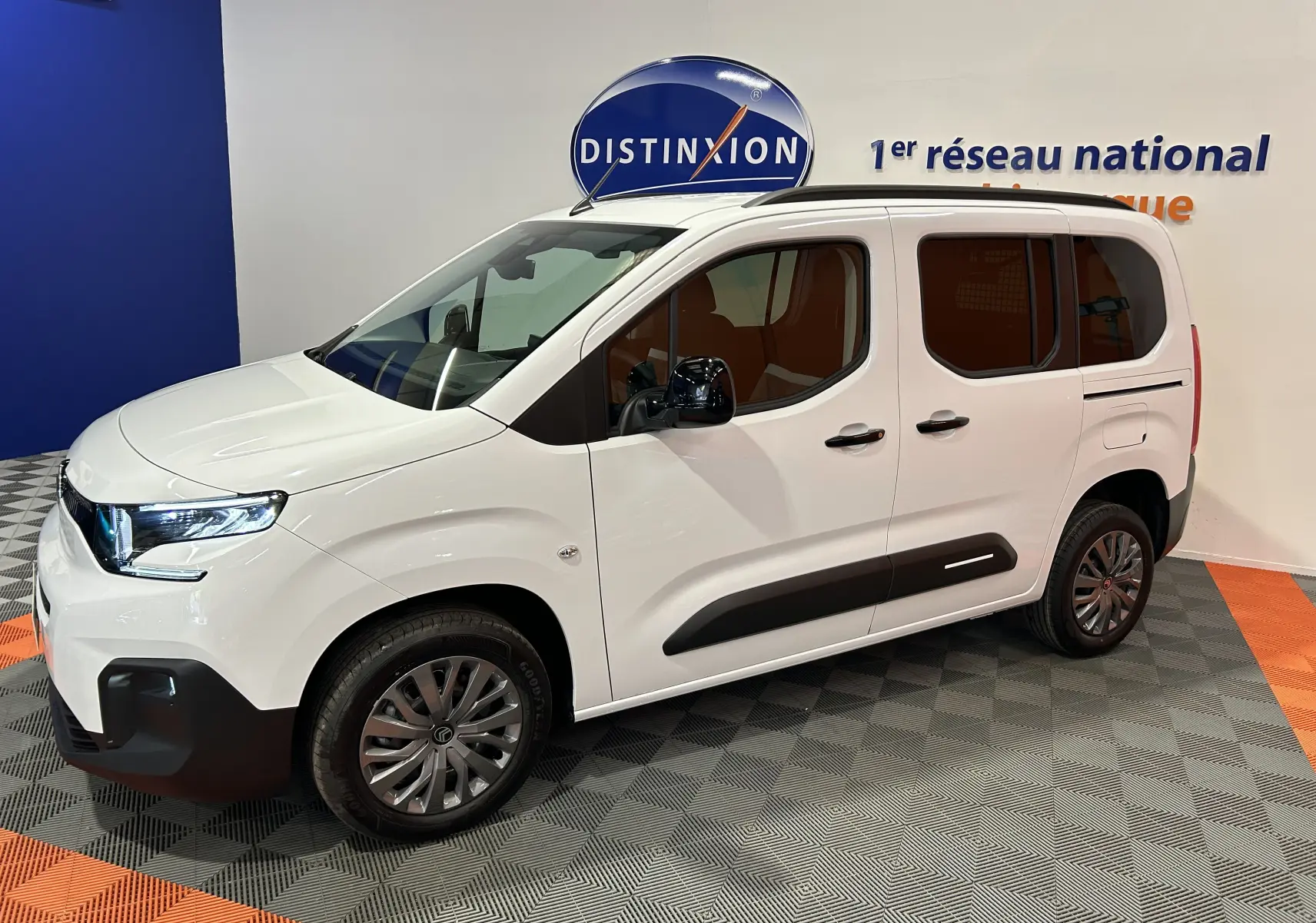 Vue 3/4 avant droit du Citroën Berlingo Multispace blanc Kaolin avec barres de toit noires et vitres surteintées.