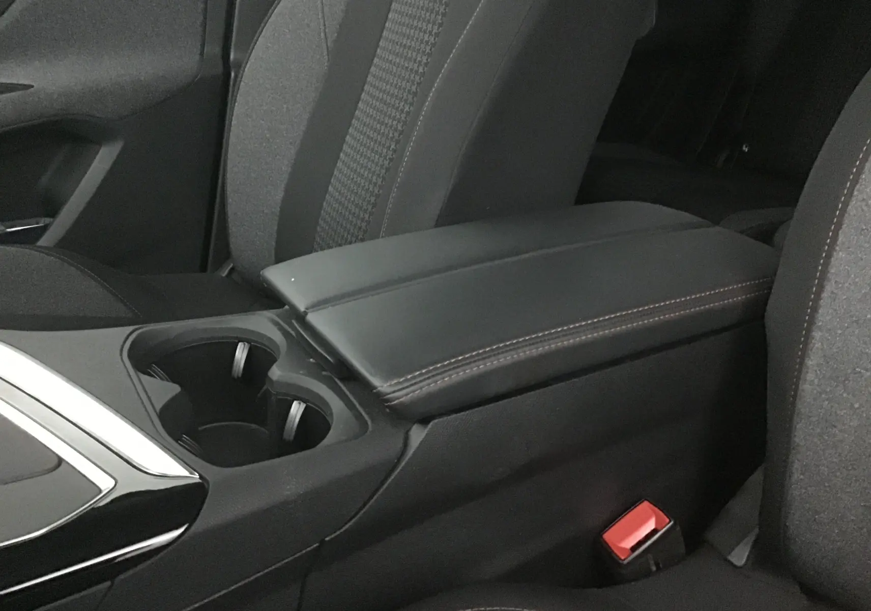 Gros plan sur l'accoudoir central en cuir noir et porte-gobelets entre les sièges avant du Peugeot 5008 noir 2019.