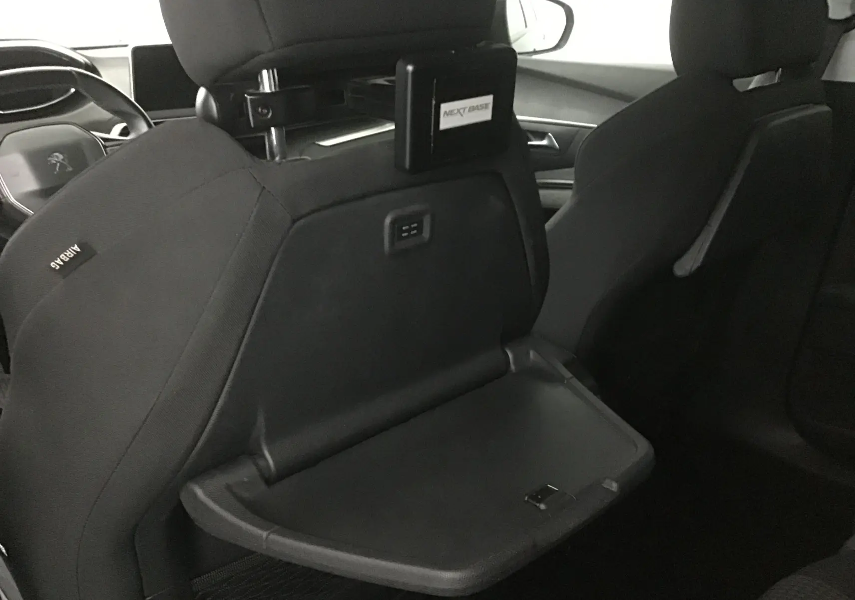 Intérieur noir du Peugeot 5008 2019, vue arrière du siège avant gauche avec tablette rabattable et support écran enfant.