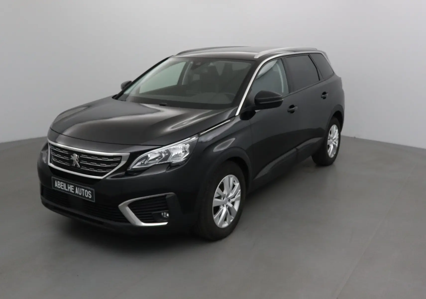 Peugeot 5008 noir en 3/4 avant droit, avec calandre chromée et jantes alliage 17 pouces visibles.