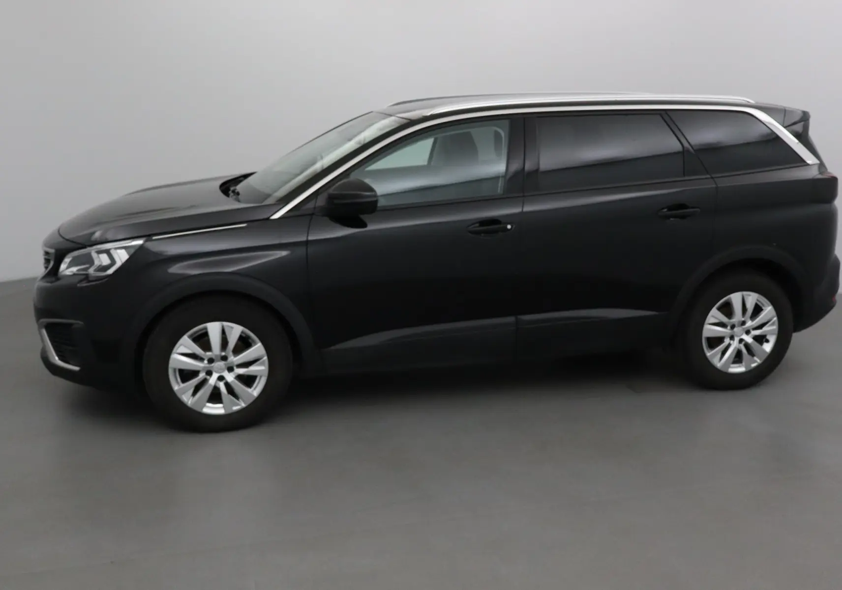 Peugeot 5008 noir vue de profil côté gauche, mettant en valeur ses lignes élégantes et ses vitres teintées.