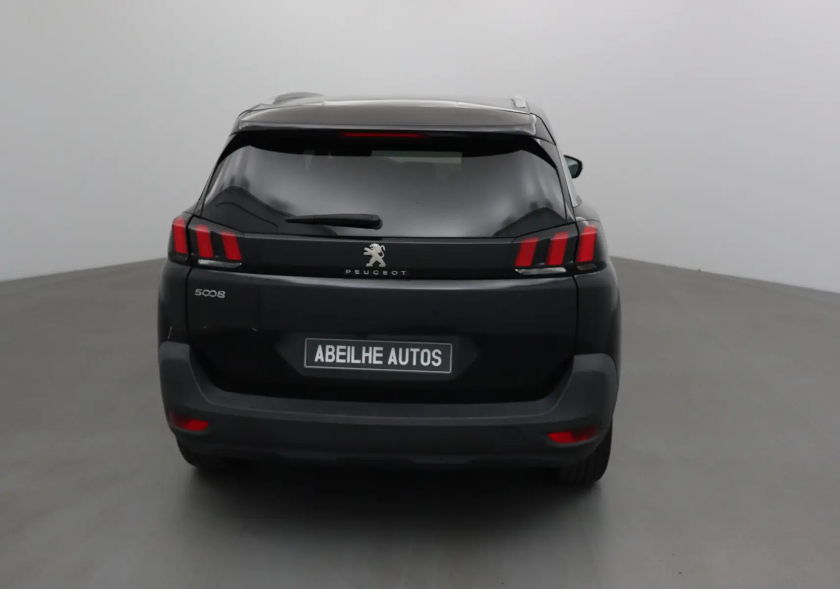Vue arrière d'un Peugeot 5008 noir avec feux arrière à trois griffes caractéristiques et plaque Abeilhe Autos.