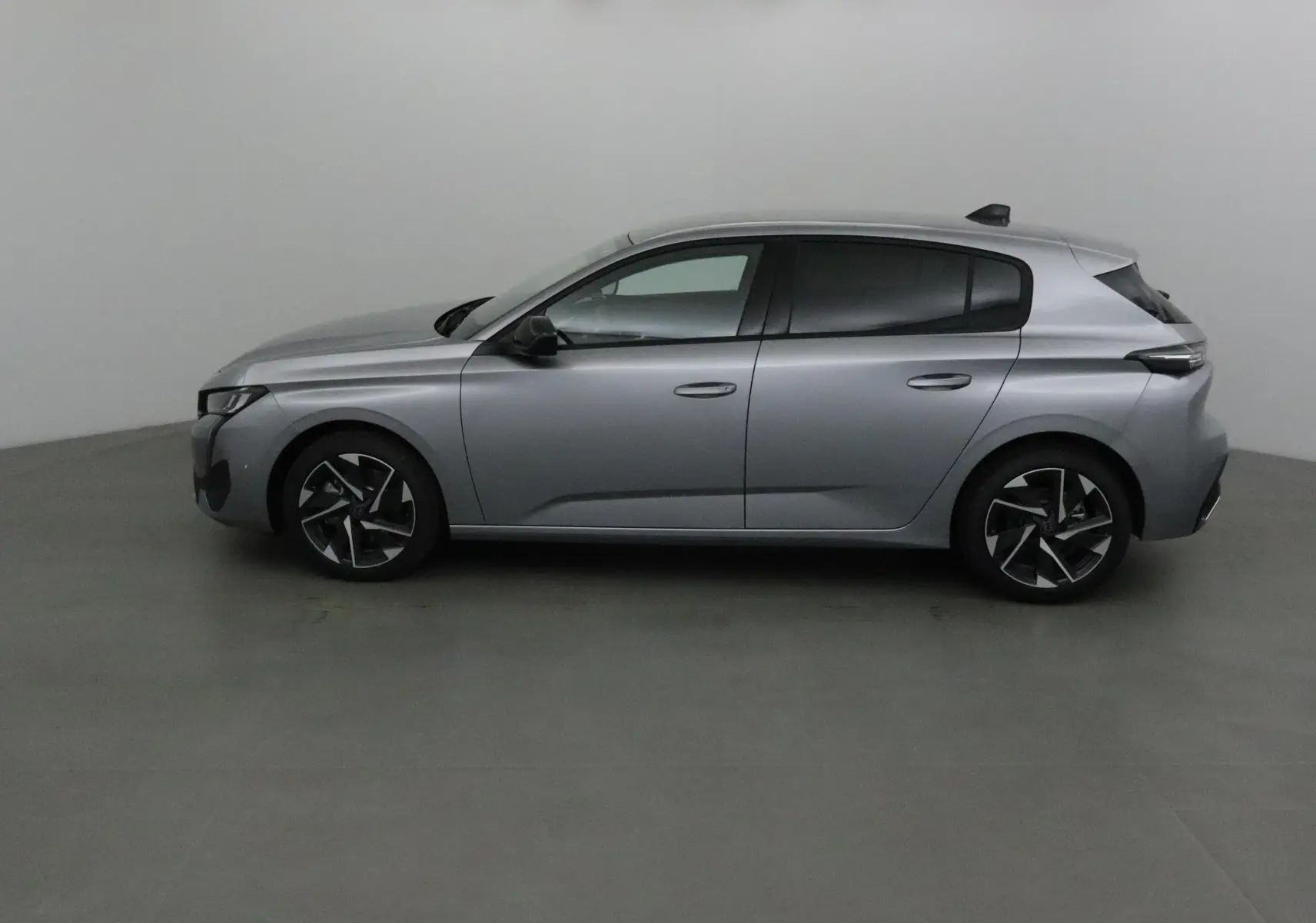 Peugeot 308 gris Artense vue de profil côté gauche, soulignant ses jantes alliage noires et lignes épurées.