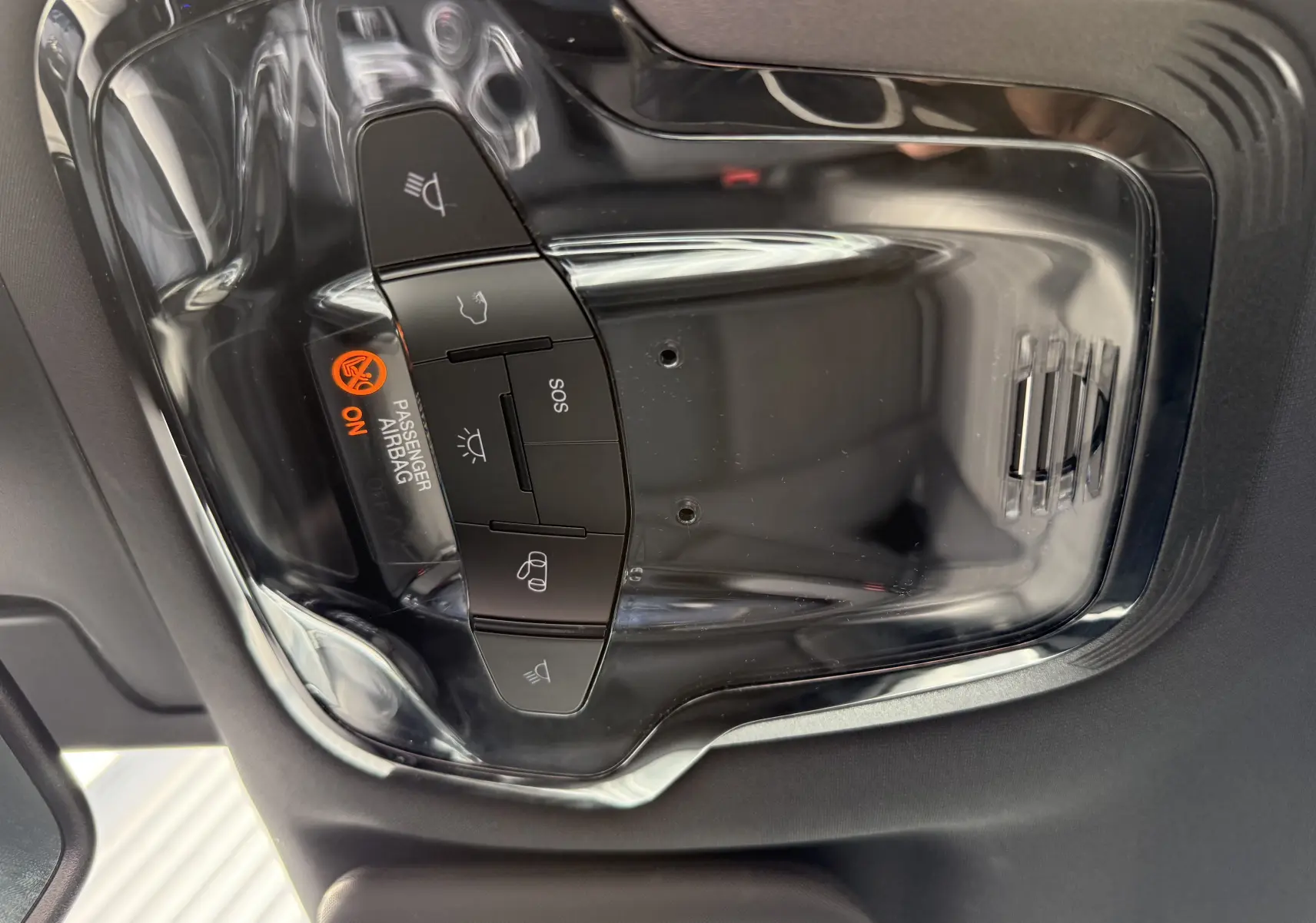 Vue en gros plan du panneau de commande intérieur noir brillant avec indicateur airbag passager activé de l'Alfa Romeo Stelvio blanc.