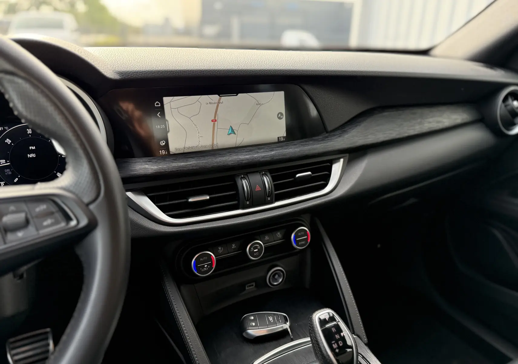Vue intérieure du tableau de bord de l'Alfa Romeo Stelvio 2023, avec écran GPS et commandes de climatisation visibles.