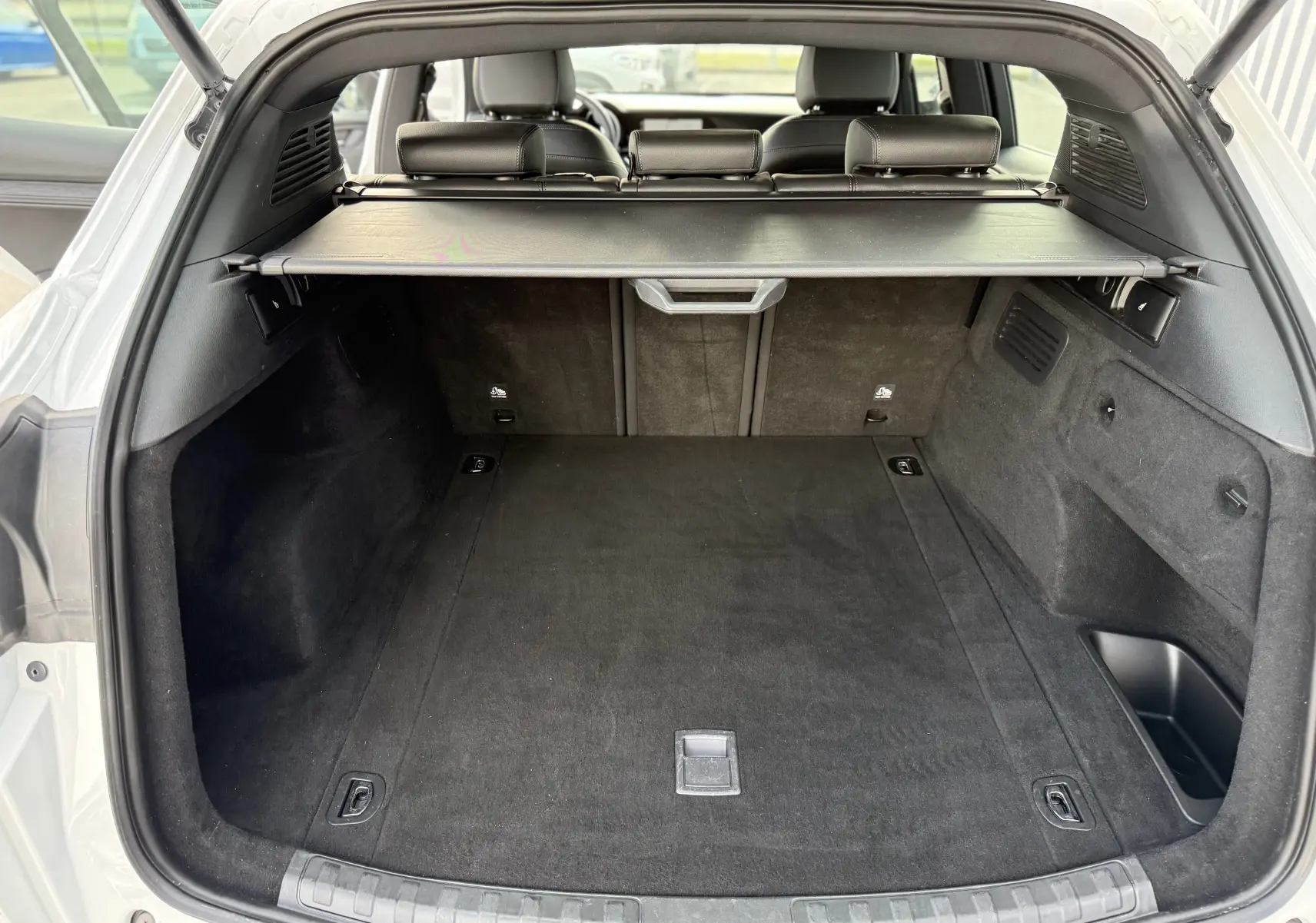 Coffre ouvert d'un Alfa Romeo Stelvio blanc Alfa 2023, vue arrière montrant l'espace de chargement avec cache-bagages noir.