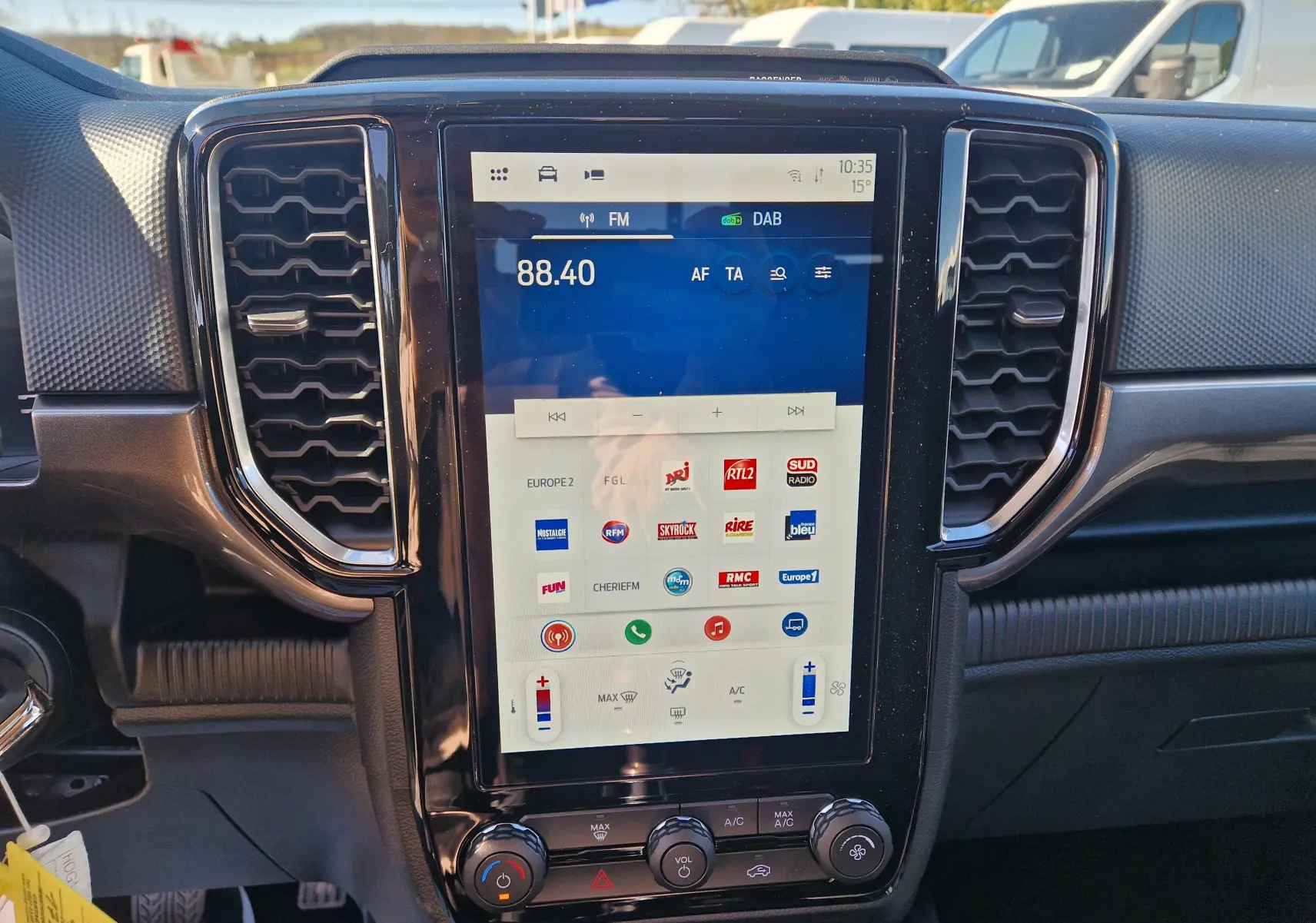 Vue rapprochée de l’écran tactile central du Ford Ranger gris Iconic 2026, avec commandes climatisation et radio visibles.