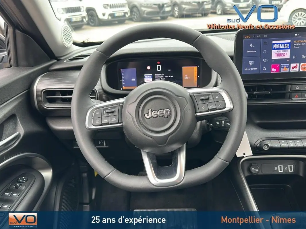 Vue intérieure du volant Jeep Avenger 2024 gris foncé, avec tableau de bord numérique et écran tactile central.