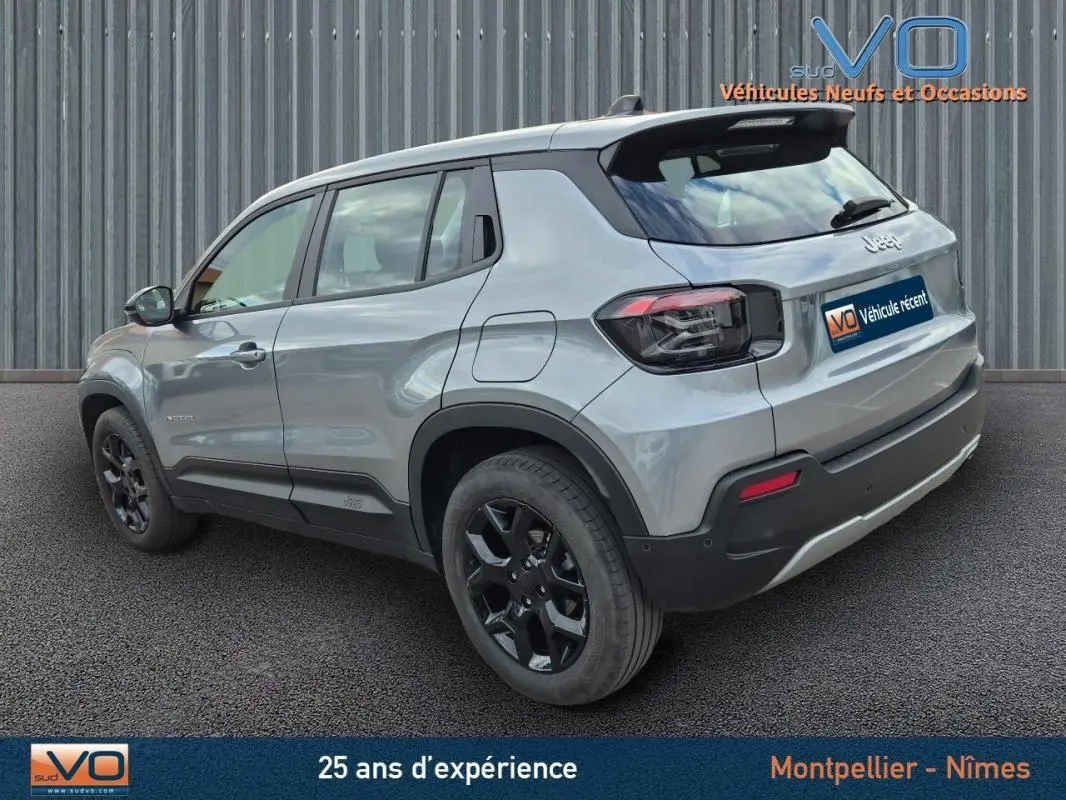 Jeep Avenger gris foncé vue 3/4 arrière côté gauche, avec jantes noires et toit noir contrastant.