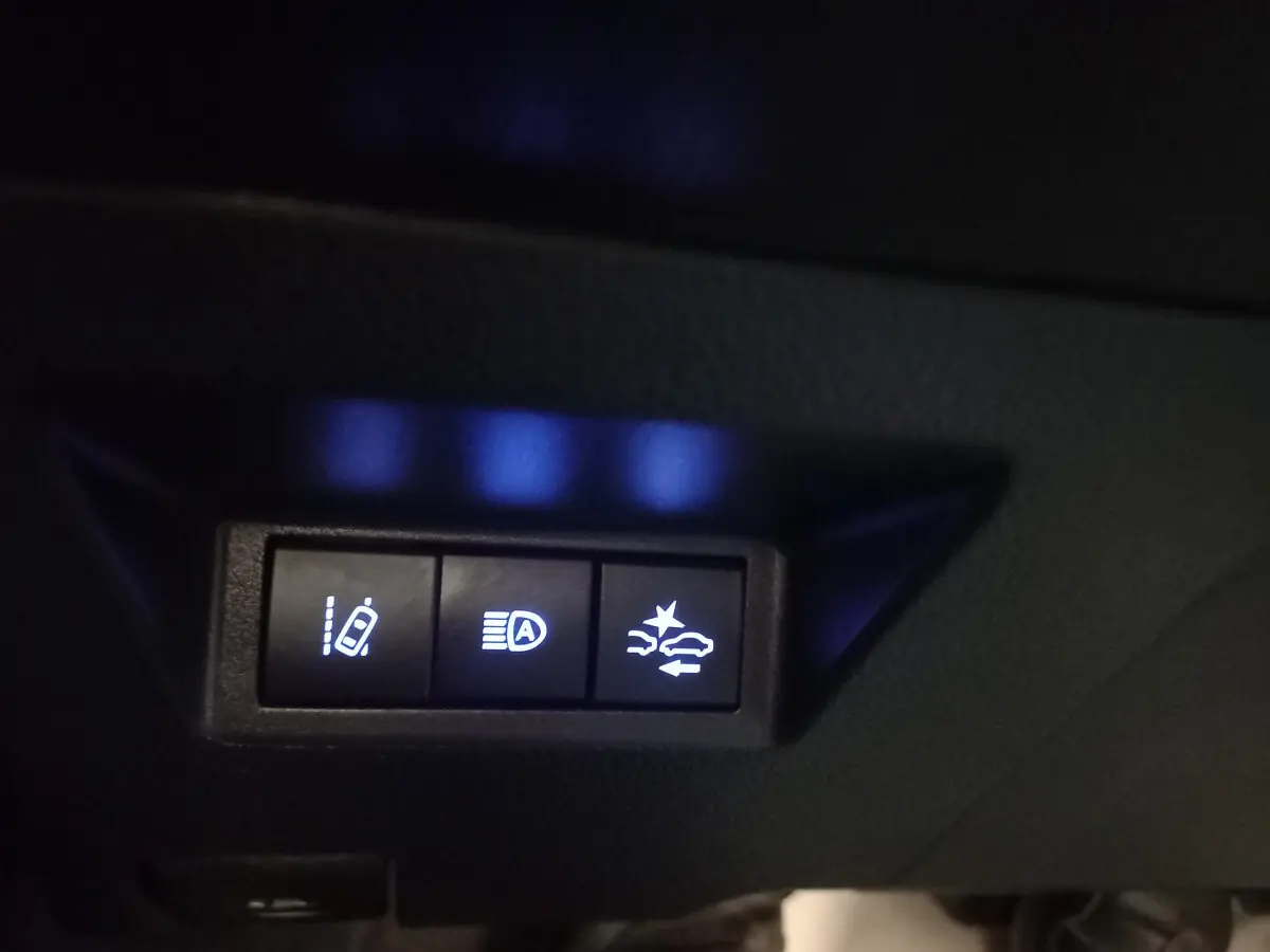 Gros plan sur les boutons de commande d'assistance à la conduite dans l'habitacle de la Toyota Yaris noire 2018.