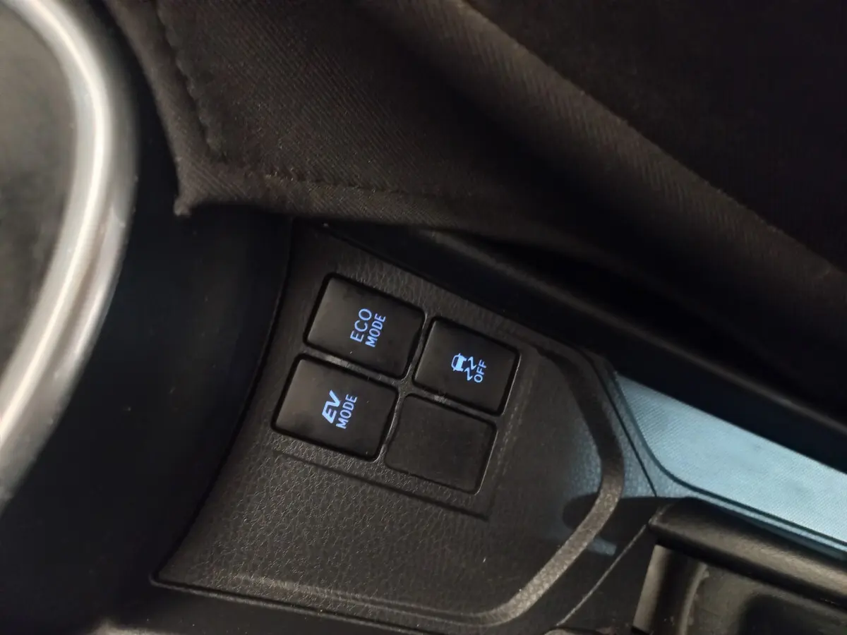 Gros plan sur les boutons de modes de conduite et contrôle de stabilité dans l'habitacle noir de la Toyota Yaris hybride 2018.