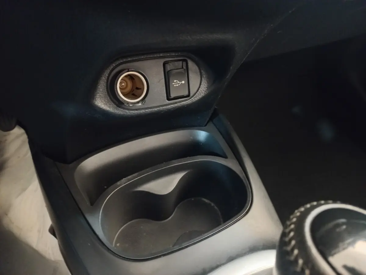 Prise 12V et port USB au-dessus des porte-gobelets dans l'habitacle noir de la Toyota Yaris hybride 2018.