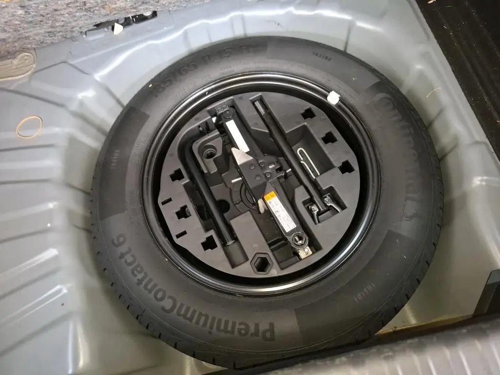 Gros plan sur la roue de secours et les outils de bord dans le coffre d'une Renault Clio Gris Titanium 2022.