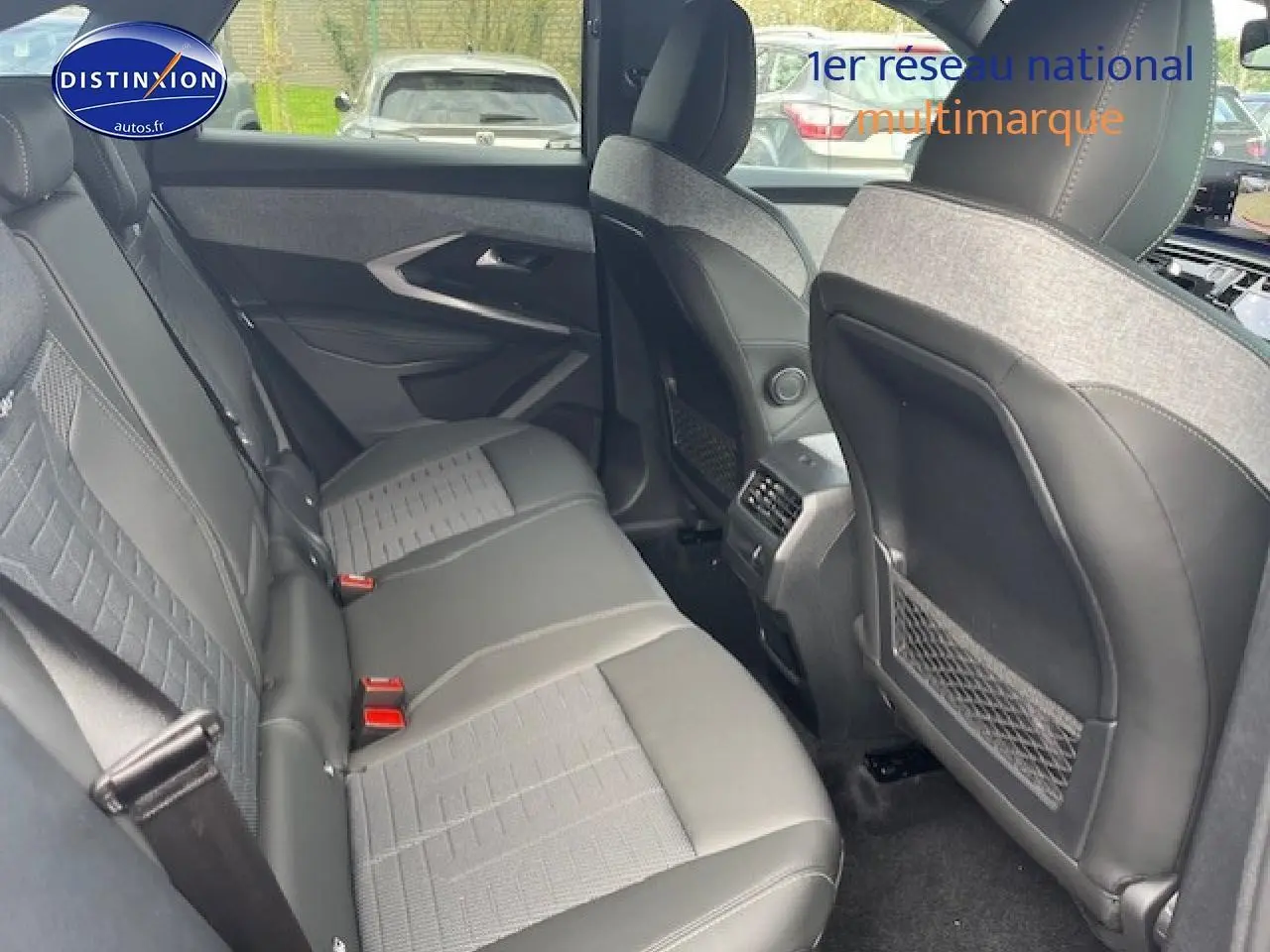 Vue intérieure arrière du Peugeot 3008 gris titane, montrant les sièges et les dossiers avant avec rangements filet.