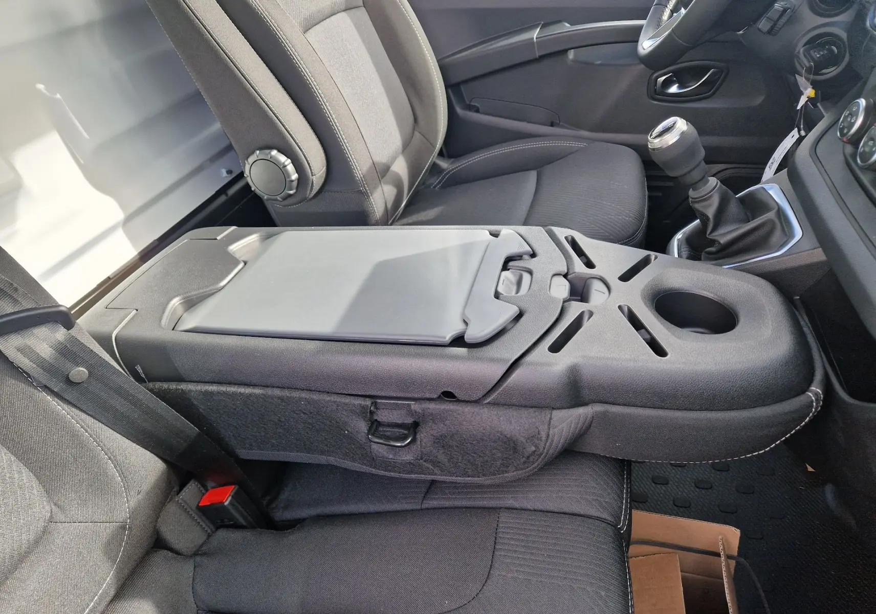 Vue intérieure côté droit du Nissan Primastar 2025, montrant les sièges noirs et la console centrale avec porte-gobelet intégré.