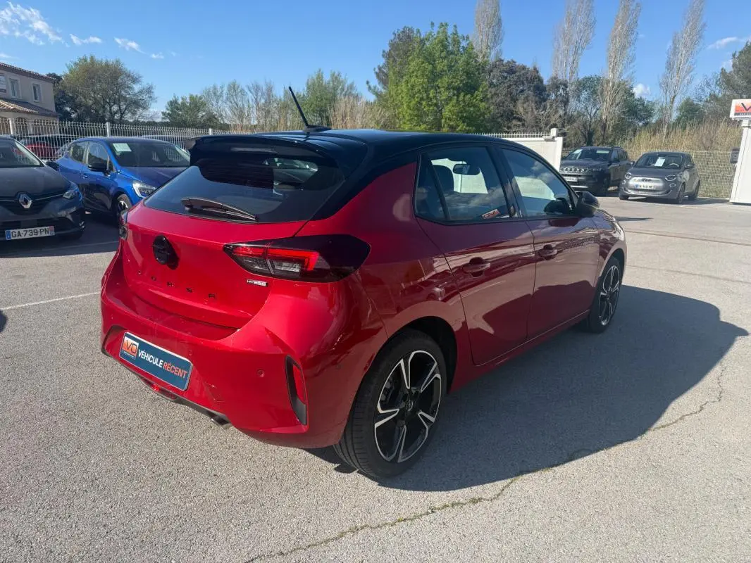 Vue 3/4 arrière droite d'une Opel Corsa rouge 2025 avec toit noir et jantes alliage distinctives.