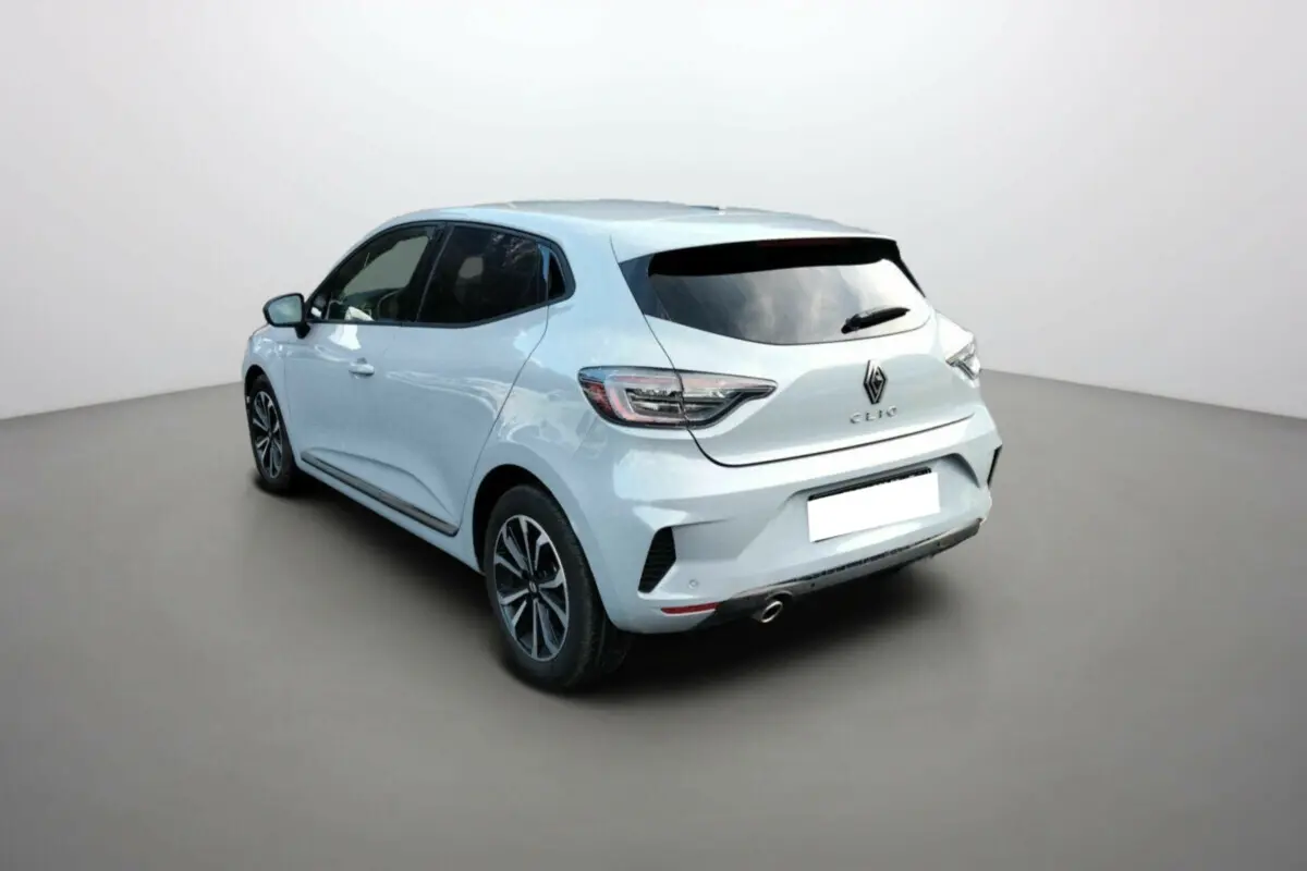 Vue 3/4 arrière droite d'une Renault Clio gris clair avec vitres surteintées et jantes alliage noires.