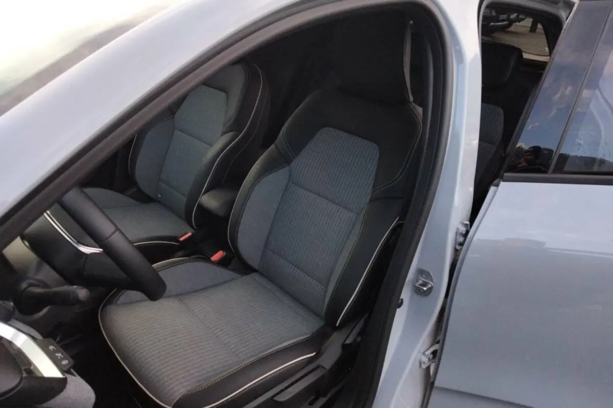 Vue intérieure côté conducteur de la Renault Clio gris rafale 2025, montrant les sièges avant en tissu et cuir noir.