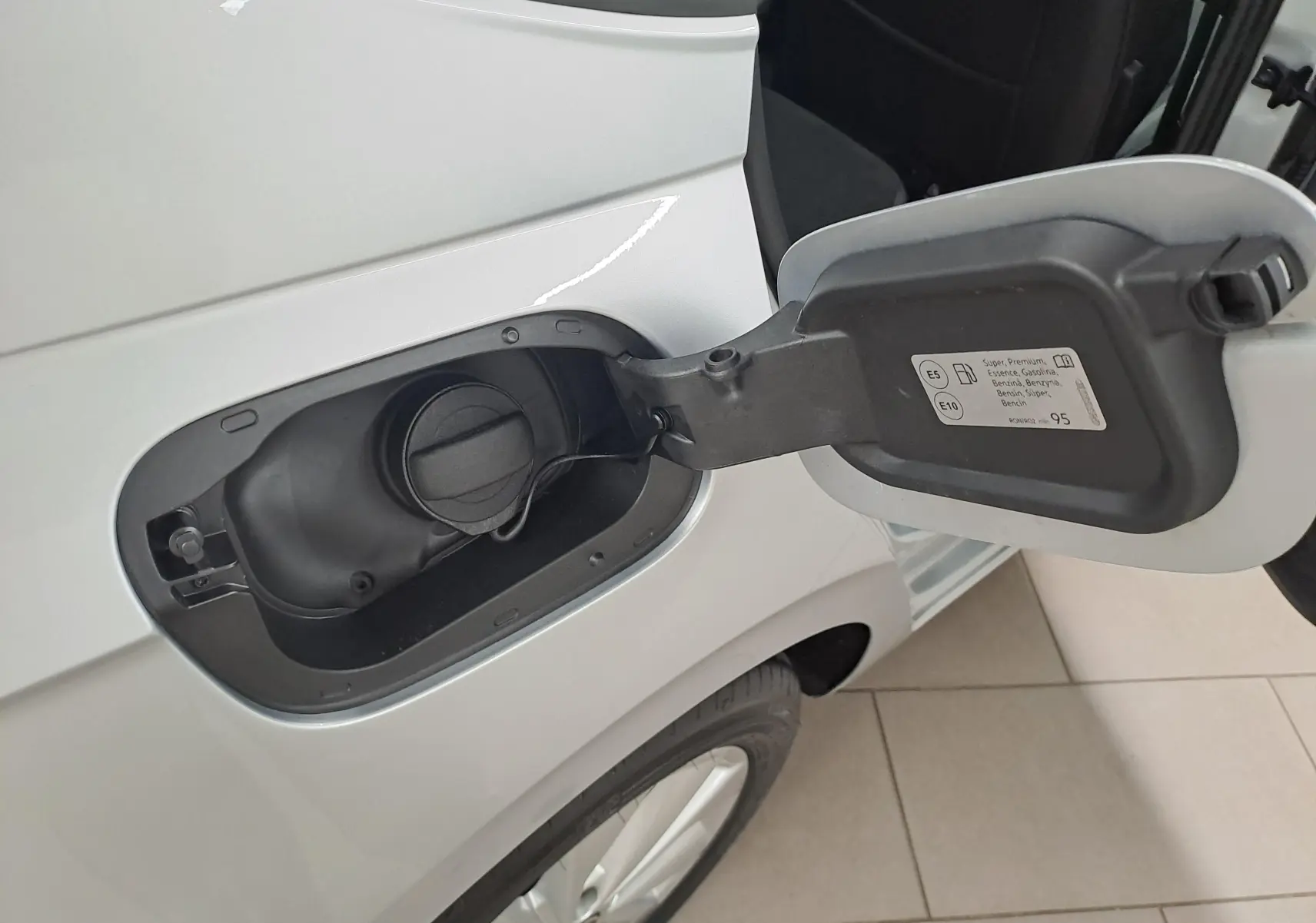Gros plan sur la trappe à carburant côté gauche d'une Volkswagen Polo 2025 couleur reflet d'argent, essence.